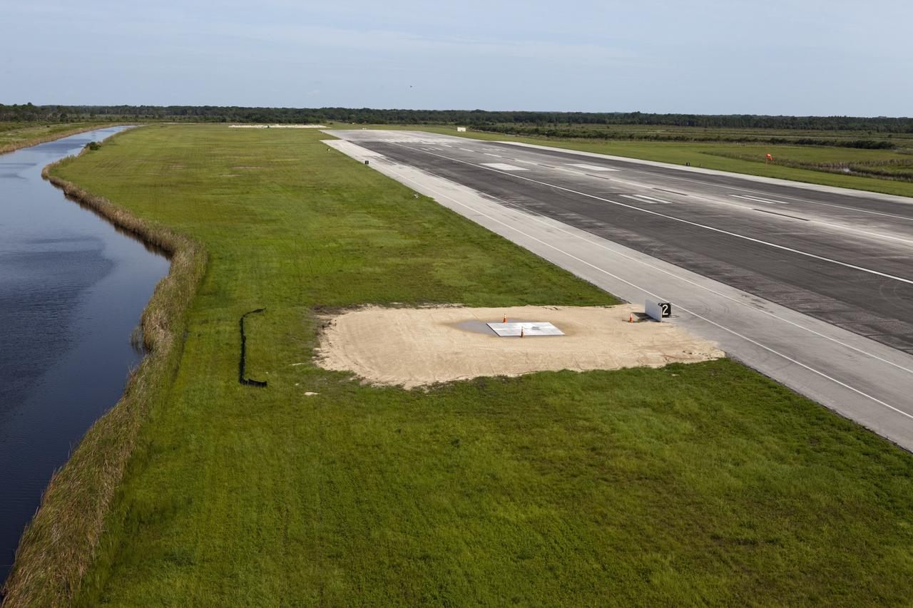 CAPE CANAVERAL, Fla. – This aerial view shows the launch platform for the Project Morpheus lander at the midfield point of the Shuttle Landing Facility, or SLF, at NASA’s Kennedy Space Center in Florida. At the north end of the runway is a rock and crater-filled planetary scape built so engineers can test the Autonomous Landing and Hazard Avoidance Technology, or ALHAT system on the Morpheus lander. Testing will demonstrate ALHAT’s ability to provide required navigation data negotiating the Morpheus lander away from risks during descent.      Checkout of the prototype lander has been ongoing at NASA’s Johnson Space Center in Houston in preparation for its first free flight. The SLF site will provide the lander with the kind of field necessary for realistic testing. Project Morpheus is one of 20 small projects comprising the Advanced Exploration Systems, or AES, program in NASA’s Human Exploration and Operations Mission Directorate. AES projects pioneer new approaches for rapidly developing prototype systems, demonstrating key capabilities and validating operational concepts for future human missions beyond Earth orbit. For more information on Project Morpheus, visit http://www.nasa.gov/centers/johnson/exploration/morpheus/index.html  Photo credit: NASA/Kim Shiflett