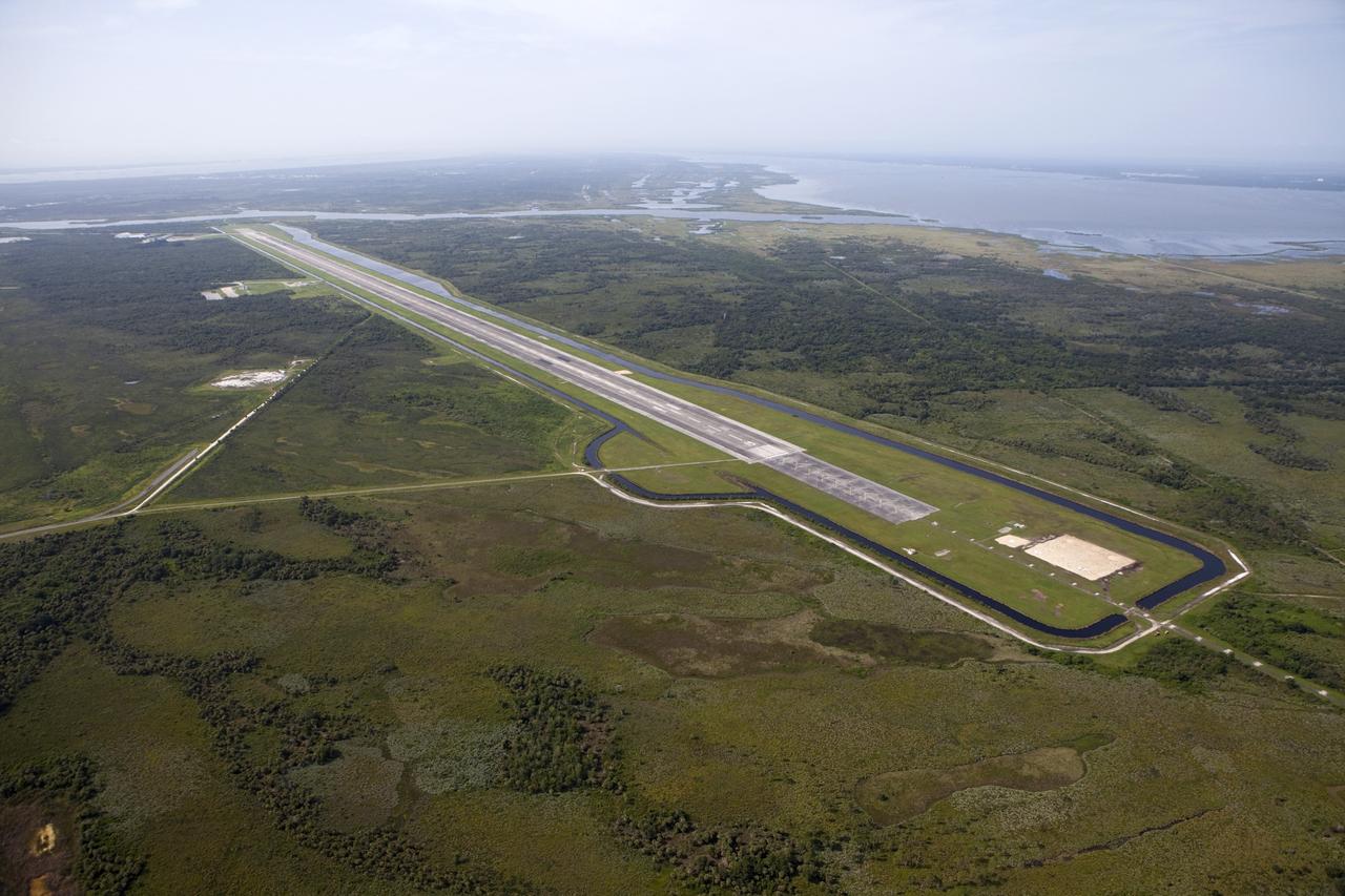 CAPE CANAVERAL, Fla. – This aerial view shows the 15,000-foot long Shuttle Landing Facility at the Kennedy Space Center, Fla. At the north end of the runway, to the right, is a rock and crater-filled planetary scape has been built so engineers can test the Autonomous Landing and Hazard Avoidance Technology, or ALHAT system on the Project Morpheus lander. Testing will demonstrate ALHAT’s ability to provide required navigation data negotiating the Morpheus lander away from risks during descent.      Checkout of the prototype lander has been ongoing at NASA’s Johnson Space Center in Houston in preparation for its first free flight. The SLF site will provide the lander with the kind of field necessary for realistic testing. Project Morpheus is one of 20 small projects comprising the Advanced Exploration Systems, or AES, program in NASA’s Human Exploration and Operations Mission Directorate. AES projects pioneer new approaches for rapidly developing prototype systems, demonstrating key capabilities and validating operational concepts for future human missions beyond Earth orbit. For more information on Project Morpheus, visit http://www.nasa.gov/centers/johnson/exploration/morpheus/index.html  Photo credit: NASA/Kim Shiflett