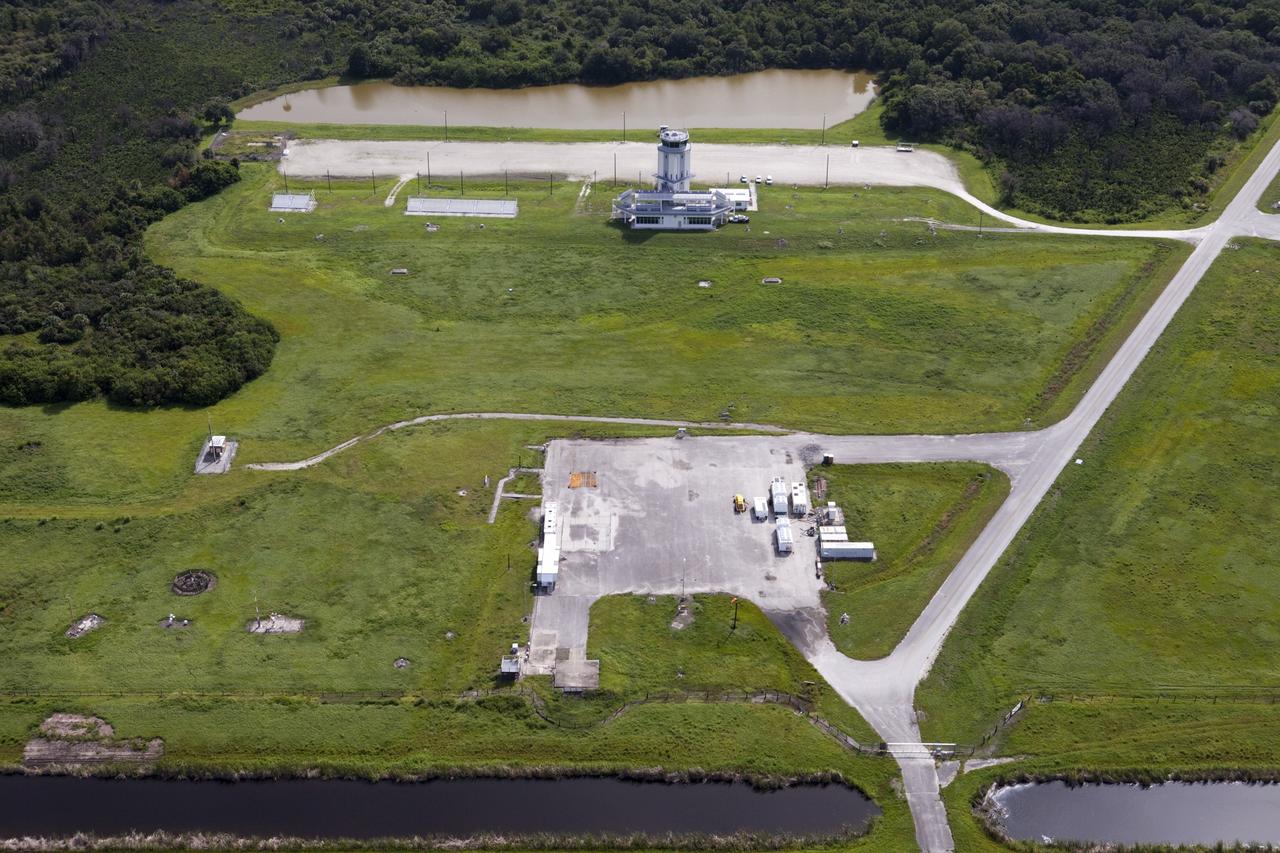 CAPE CANAVERAL, Fla. – This aerial view shows the Shuttle Landing Facility’s air traffic control tower at the Kennedy Space Center in Florida. Just below the tower is the mid-field park site used for runway support vehicles. At the north end of the runway, a rock and crater-filled planetary scape has been built so engineers can test the Autonomous Landing and Hazard Avoidance Technology, or ALHAT system on the Project Morpheus lander. Testing will demonstrate ALHAT’s ability to provide required navigation data negotiating the Morpheus lander away from risks during descent.      Checkout of the prototype lander has been ongoing at NASA’s Johnson Space Center in Houston in preparation for its first free flight. The SLF site will provide the lander with the kind of field necessary for realistic testing. Project Morpheus is one of 20 small projects comprising the Advanced Exploration Systems, or AES, program in NASA’s Human Exploration and Operations Mission Directorate. AES projects pioneer new approaches for rapidly developing prototype systems, demonstrating key capabilities and validating operational concepts for future human missions beyond Earth orbit. For more information on Project Morpheus, visit http://www.nasa.gov/centers/johnson/exploration/morpheus/index.html  Photo credit: NASA/Kim Shiflett