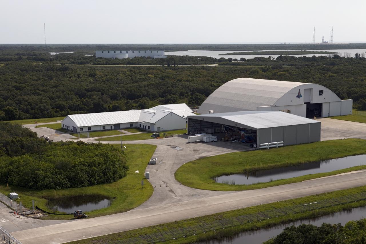 CAPE CANAVERAL, Fla. – This aerial view shows a 50,000-square-foot hangar located on the Shuttle Landing Facility at the Kennedy Space Center, Fla., providing shelter and storage for NASA and non-NASA aircraft and maintenance operations. Adjacent to the hangar is an operations building housing personnel who support operations at the 15,000-foot long concrete runway. At the north end of the runway, a rock and crater-filled planetary scape has been built so engineers can test the Autonomous Landing and Hazard Avoidance Technology, or ALHAT system on the Project Morpheus lander. Testing will demonstrate ALHAT’s ability to provide required navigation data negotiating the Morpheus lander away from risks during descent.      Checkout of the prototype lander has been ongoing at NASA’s Johnson Space Center in Houston in preparation for its first free flight. The SLF site will provide the lander with the kind of field necessary for realistic testing. Project Morpheus is one of 20 small projects comprising the Advanced Exploration Systems, or AES, program in NASA’s Human Exploration and Operations Mission Directorate. AES projects pioneer new approaches for rapidly developing prototype systems, demonstrating key capabilities and validating operational concepts for future human missions beyond Earth orbit. For more information on Project Morpheus, visit http://www.nasa.gov/centers/johnson/exploration/morpheus/index.html  Photo credit: NASA/Kim Shiflett