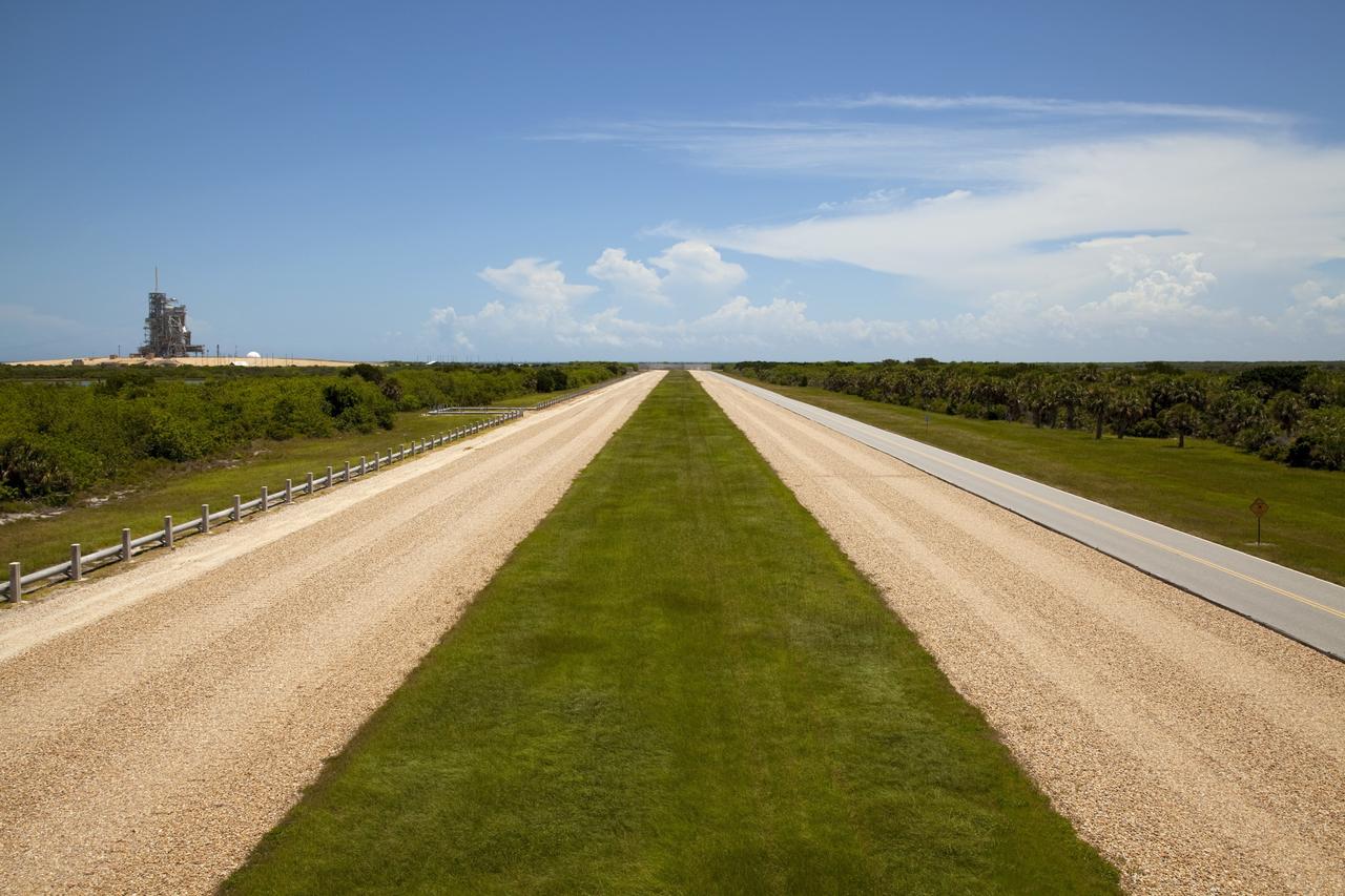 CAPE CANAVERAL, Fla. – The gravel crawlerway is seen as if from a crawler transporter approaching Launch Complex 39 pad A at the Kennedy Space Center in Florida. The crawlerways are 130 feet wide, about the size of an 8-lane freeway. The river rock paths have been used since 1966 to move launch vehicles from the Vehicle Assembly Building, or VAB, along the 3.4-mile path to pad A and 6.8 miles to pad B. The crawlerways were originally built to support transporting Apollo Saturn V rockets to the launch pads. The crawlerways were again used during the Space Shuttle Program moving the 4.5 million-pound shuttles mounted on an 8-million-pound mobile launcher platform atop a six-million-pound crawler transporter -- totaling an 18.5-million-pound vehicle lumbering along to the pad. The paths are specially constructed with four layers. The top is eight inches thick on curves and four inches on straightaway sections. Then there is a four-foot layer of graded, crushed stone. Beneath that is 2.5 feet of fill, followed by one foot of compact fill. Plans call for the crawlerways to be used in the future for transporting launch vehicles from the VAB to pads A and B. For more information, visit http://www.nasa.gov/transition Photo credit: NASA/Kim Shiflett