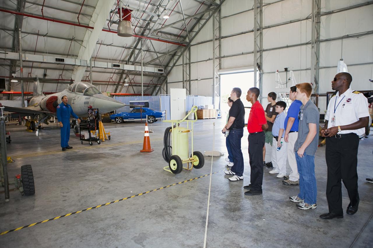 CAPE CANAVERAL, Fla. – Inside the RLV Hangar near NASA Kennedy Space Center’s Shuttle Landing Facility, or SLF, in Florida, students and their flight instructors from Florida Tech, FIT, in Melbourne view F104 Starfighter aircraft and hear a presentation from Starfighter Director Rick Svetkoff. The group arrived at the SLF in Cherokee Warrior and Cessna 172S lightweight aircraft.    The middle and high school students are participating in FIT’s Av/Aero summer camp experience. They and their flight instructors toured the SLF midfield control tower, viewed F104 Starfighters and NASA Huey helicopters in the RLV Hangar, viewed the runway plaques marking wheels stop for each of the three space shuttles, and toured the Vehicle Assembly Building where space shuttle Atlantis currently is stored. Photo credit: NASA/Kim Shiflett