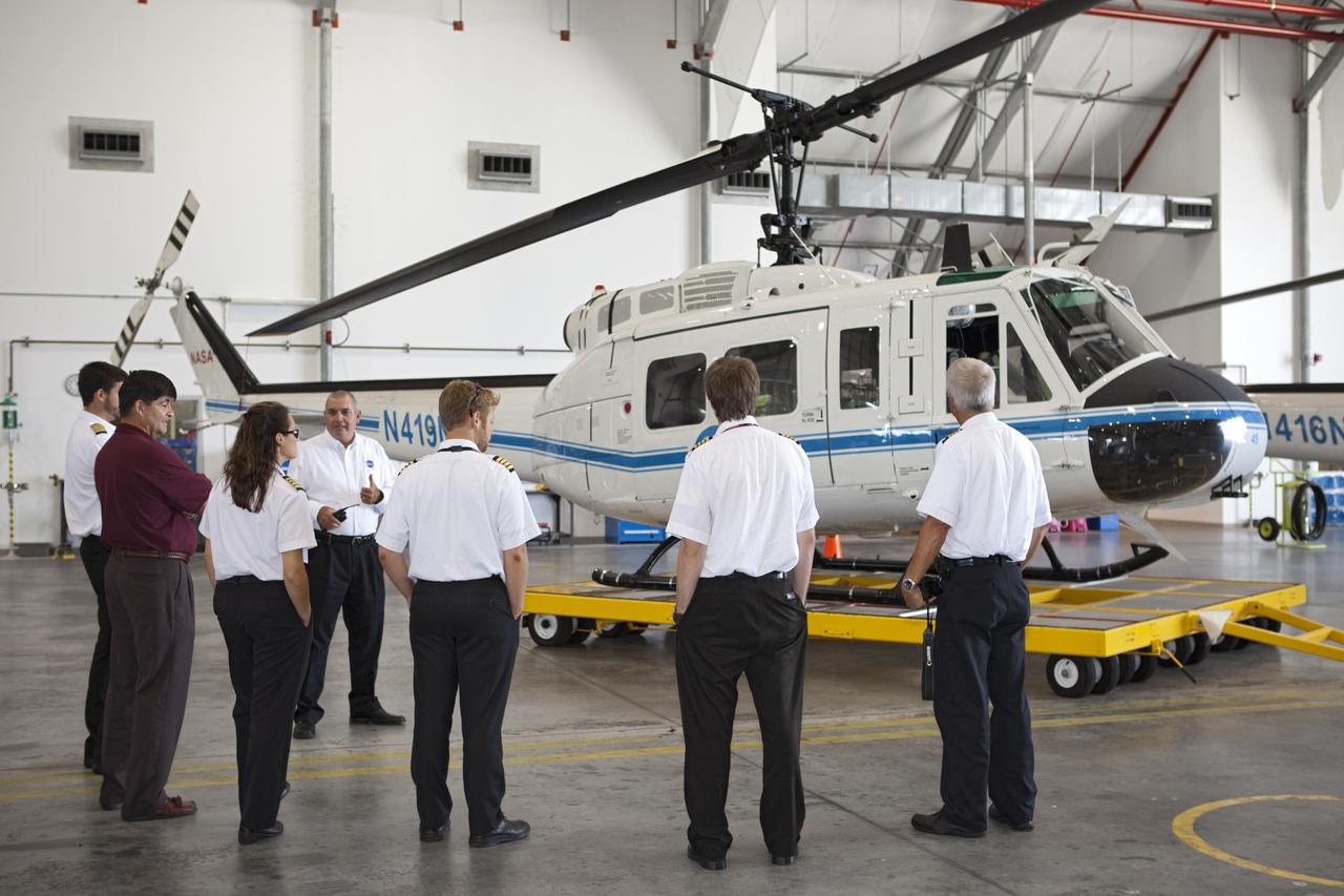 CAPE CANAVERAL, Fla. – Inside the RLV Hangar near NASA Kennedy Space Center’s Shuttle Landing Facility, or SLF, in Florida, flight instructors from Florida Tech, FIT, in Melbourne, listen to NASA Aviation Safety Officer Joe Torsani and view a NASA Huey helicopter. At left, in the red shirt is Glenn Vera, director of FIT Aviation. The flight instructors and their students arrived at the SLF in Cherokee Warrior and Cessna 172S lightweight aircraft.    The middle and high school students are participating in FIT’s Av/Aero summer camp experience. They and their flight instructors toured the SLF midfield control tower, viewed F104 Starfighters and NASA Huey helicopters in the RLV Hangar, viewed the runway plaques marking wheels stop for each of the three space shuttles, and toured the Vehicle Assembly Building where space shuttle Atlantis currently is stored. Photo credit: NASA/Kim Shiflett