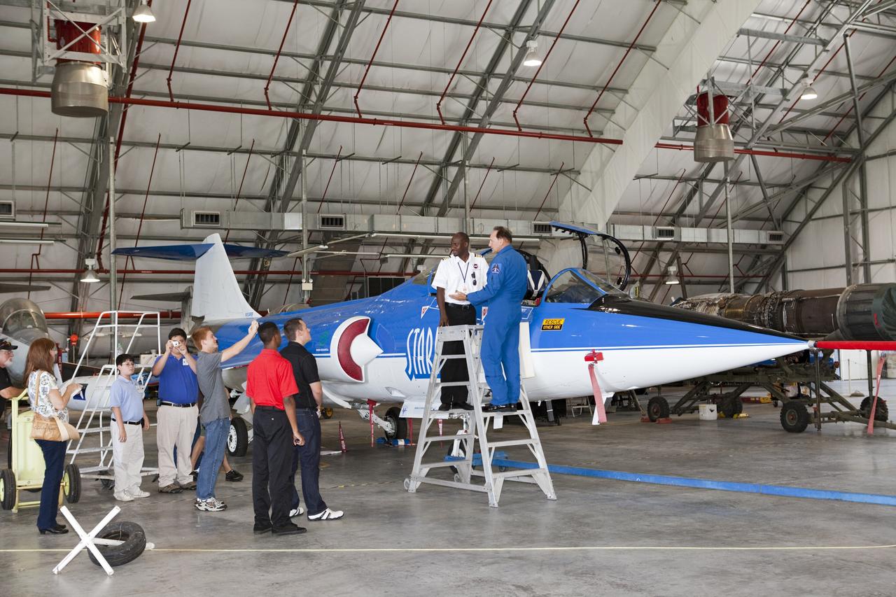 CAPE CANAVERAL, Fla. – Inside the RLV Hangar near NASA Kennedy Space Center’s Shuttle Landing Facility, or SLF, in Florida, Florida Tech, or FIT, Aviation Program Supervisor Tennesse Garvey, at left on the ladder, and several students view an F104 Starfighter. At right, on the ladder is Starfighter Director Rick Svetkoff. The FIT aviation instructors and their students arrived at the SLF in Cherokee Warrior and Cessna 172S lightweight aircraft.    The middle and high school students are participating in FIT’s Av/Aero summer camp experience. They and their flight instructors toured the SLF midfield control tower, viewed F104 Starfighters and NASA Huey helicopters in the RLV Hangar, viewed the runway plaques marking wheels stop for each of the three space shuttles, and toured the Vehicle Assembly Building where space shuttle Atlantis currently is stored. Photo credit: NASA/Kim Shiflett
