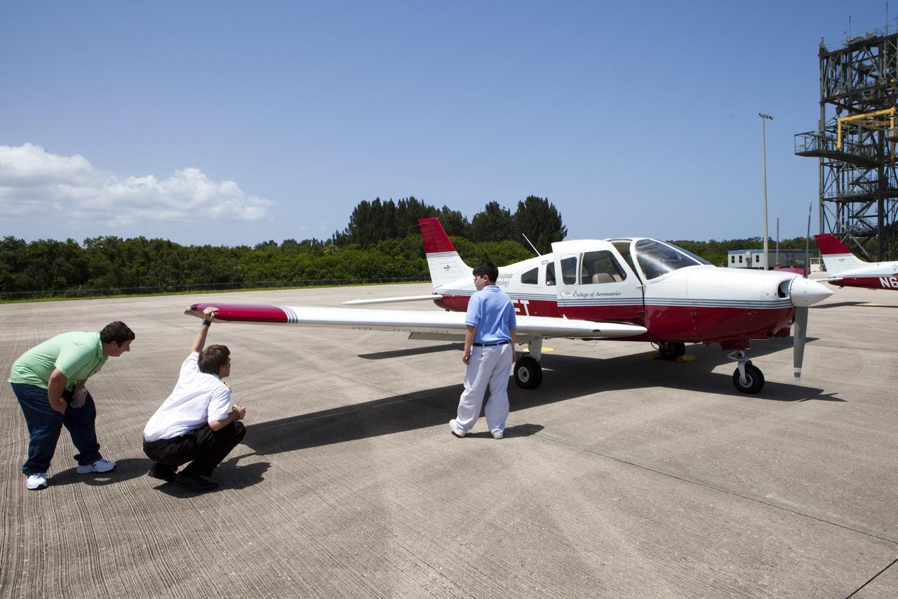 CAPE CANAVERAL, Fla. – At NASA Kennedy Space Center’s Shuttle Landing Facility, or SLF, in Florida, a flight instructor and his students inspect the lightweight aircraft they flew in earlier in the day from Florida Tech, or FIT, in Melbourne. Several instructors and their students arrived at the SLF in Cherokee Warrior and Cessna 172S lightweight aircraft.    The middle and high school students are participating in FIT’s Av/Aero summer camp experience. They and their flight instructors toured the SLF midfield control tower, viewed F104 Starfighters and NASA Huey helicopters in the RLV Hangar, viewed the runway plaques marking wheels stop for each of the three space shuttles, and toured the Vehicle Assembly Building where space shuttle Atlantis currently is stored. Photo credit: NASA/Kim Shiflett