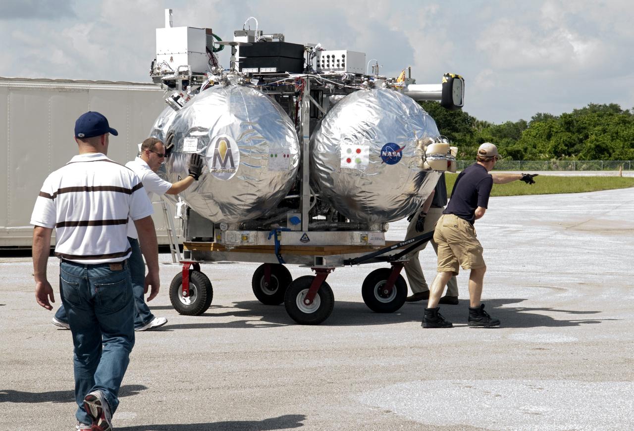 CAPE CANAVERAL, Fla. - NASA's Morpheus lander, a vertical test bed vehicle, is moved into a building at the Shuttle Landing Facility, or SLF, at the Kennedy Space Center in Florida. Morpheus is designed to demonstrate new green propellant propulsion systems and autonomous landing and an Autonomous Landing and Hazard Avoidance Technology, or ALHAT, system.      Checkout of the prototype lander has been ongoing at NASA’s Johnson Space Center in Houston in preparation for its first free flight. The SLF site will provide the lander with the kind of field necessary for realistic testing. Project Morpheus is one of 20 small projects comprising the Advanced Exploration Systems, or AES, program in NASA’s Human Exploration and Operations Mission Directorate. AES projects pioneer new approaches for rapidly developing prototype systems, demonstrating key capabilities and validating operational concepts for future human missions beyond Earth orbit. For more information on Project Morpheus, visit http://www.nasa.gov/centers/johnson/exploration/morpheus/index.html  Photo credit: NASA/ Charisse Nahser