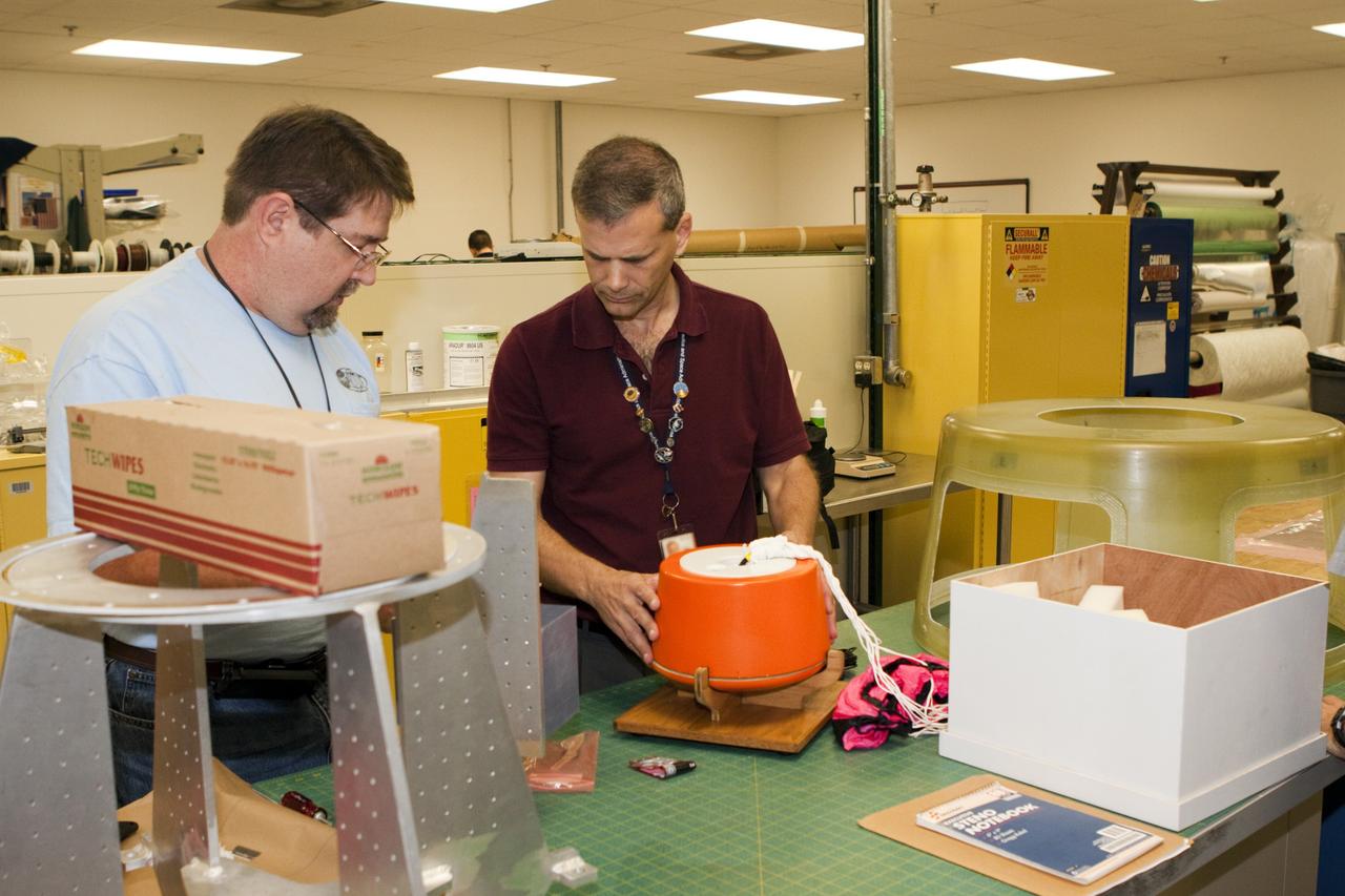 CAPE CANAVERAL, Fla. – Mike Lane, left, and Paul Paulick, both participants in the Rocket University program, inspect a capsule that is being prepared for a high-altitude balloon flight. The test flight was used to evaluate the stability of an instrumented capsule as it fell to Earth before its parachute opened. Rocket University is a program of courses, workshops, labs and projects offered to engineering and research pros of all stripes to keep their skills fresh and broaden their experiences. Photo credit: NASA/Jim Grossmann