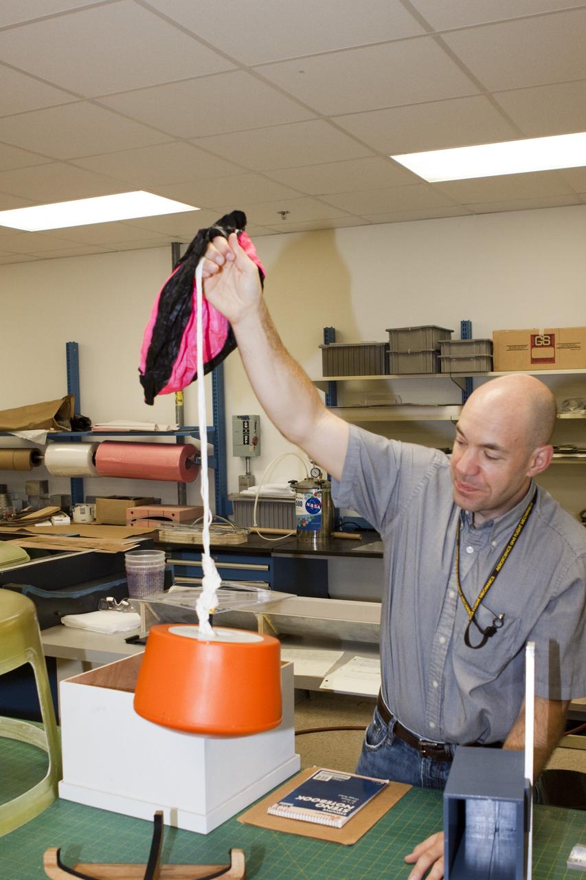 CAPE CANAVERAL, Fla. – Ron Sterick, a participant in the Rocket University program, inspects a capsule and parachute that are being prepared for a high-altitude balloon flight. The test flight was used to evaluate the stability of an instrumented capsule as it fell to Earth before its parachute opened. Rocket University is a program of courses, workshops, labs and projects offered to engineering and research pros of all stripes to keep their skills fresh and broaden their experiences. Photo credit: NASA/Jim Grossmann
