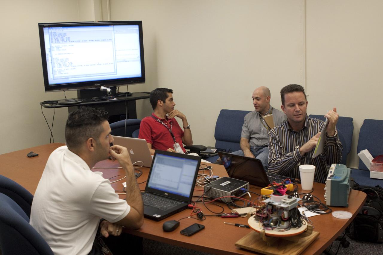 CAPE CANAVERAL, Fla. – Leandro James, left to right, Alejandro Azocar, Ron Sterick and Chris Iannello discuss a high-altitude balloon flight for the Rocket University program. The test flight was used to evaluate the stability of an instrumented capsule as it fell to Earth before its parachute opened. Rocket University is a program of courses, workshops, labs and projects offered to engineering and research pros of all stripes to keep their skills fresh and broaden their experiences. Photo credit: NASA/Jim Grossmann