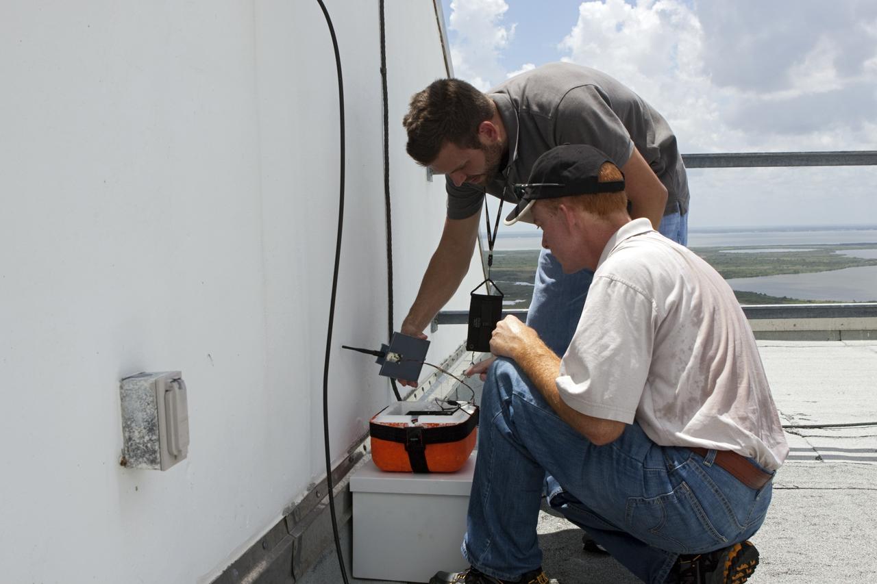 CAPE CANAVERAL, Fla. – Karl Stolleis, kneeling, and Nick Pack prepare an instrument package for testing as part of a high-altitude balloon flight for the Rocket University program. The test flight was used to evaluate the stability of an instrumented capsule as it fell to Earth before its parachute opened. Rocket University is a program of courses, workshops, labs and projects offered to engineering and research pros of all stripes to keep their skills fresh and broaden their experiences. Photo credit: NASA/Jim Grossmann
