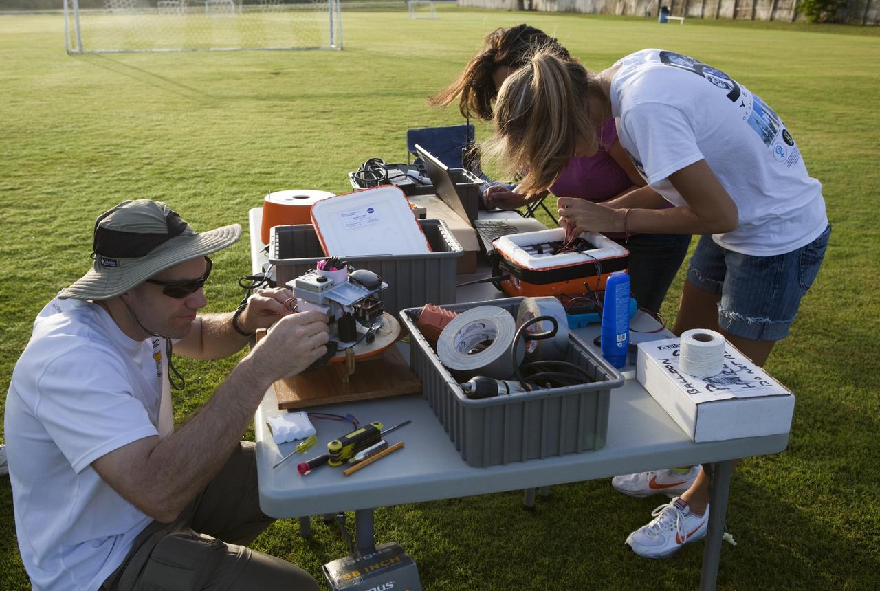 CAPE CANAVERAL, Fla. – Ron Sterick, left to right, Nicole Otermat and Page Attany, participants in the Rocket University program, prepare an instrument package to launch on a high-altitude balloon flight. The test flight was used to evaluate the stability of an instrumented capsule as it fell to Earth before its parachute opened. Rocket University is a program of courses, workshops, labs and projects offered to engineering and research pros of all stripes to keep their skills fresh and broaden their experiences. Photo credit: NASA/Jim Grossmann