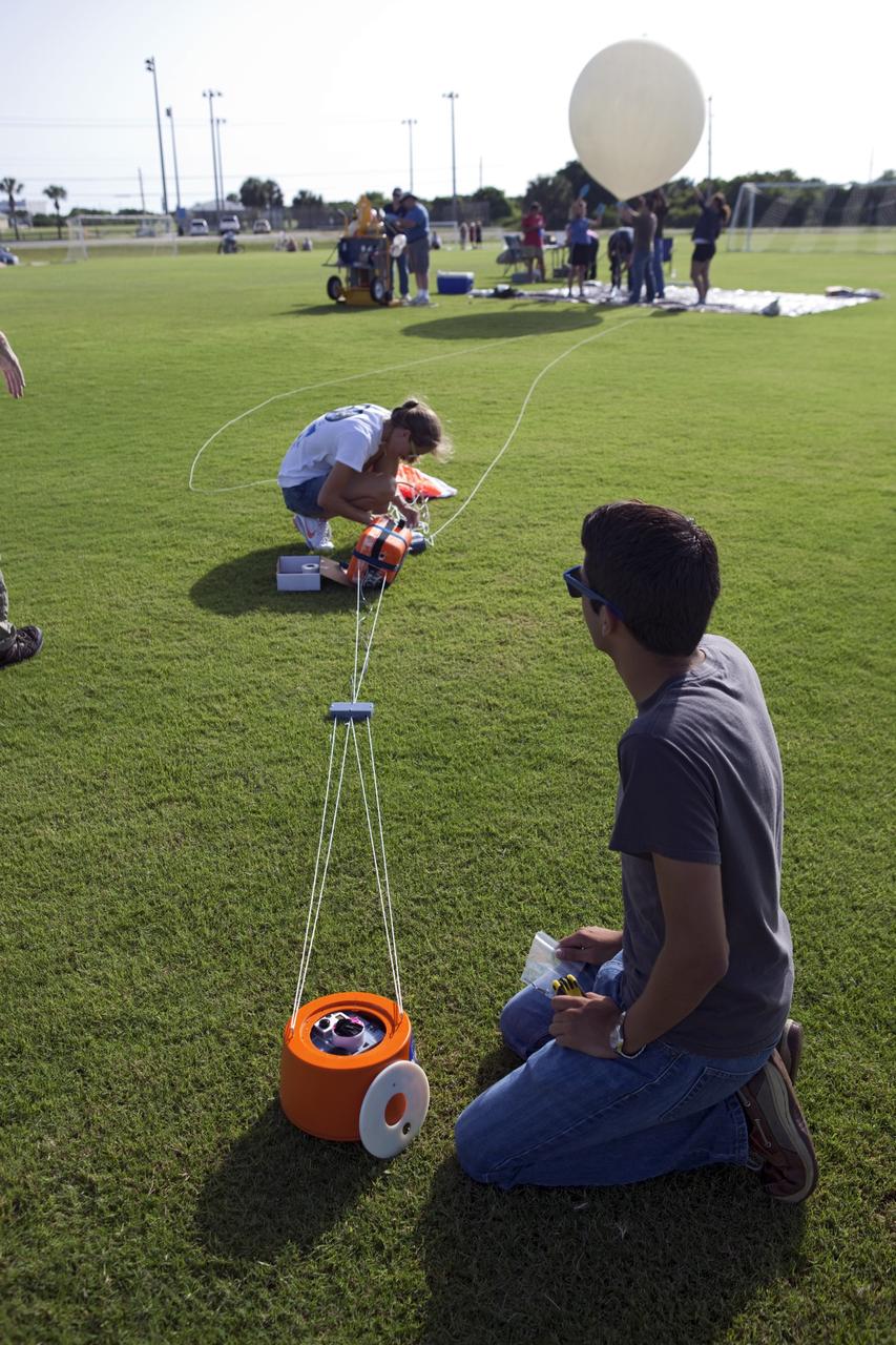 CAPE CANAVERAL, Fla. – Alejandro Azocar, foreground, and Page Attany, Rocket University participants, prepare an instrument package to launch on a high-altitude balloon flight. The test flight was used to evaluate the stability of an instrumented capsule as it fell to Earth before its parachute opened. Rocket University is a program of courses, workshops, labs and projects offered to engineering and research pros of all stripes to keep their skills fresh and broaden their experiences. Photo credit: NASA/Jim Grossmann