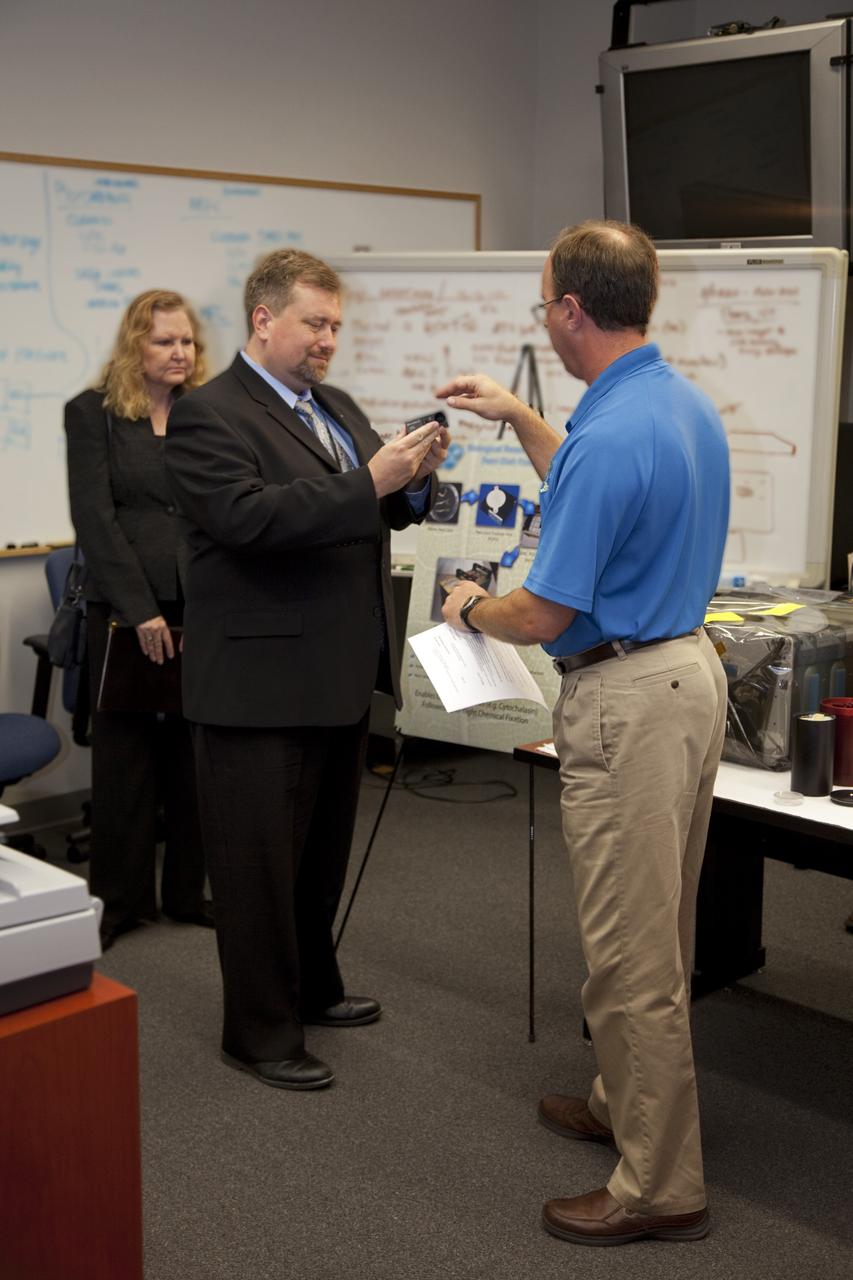 CAPE CANAVERAL, Fla. – Dr. Mason Peck, center, NASA's chief Technologist, listens as David Reed, right, explains an innovation during Pecks' tour of the Space Life Sciences Laboratory at Kennedy. Karen L. Thompson, chief technologist for Kennedy Space Center, looks on. Peck toured the lab facility during a visit to the space center. Photo credit: NASA/Frankie Martin