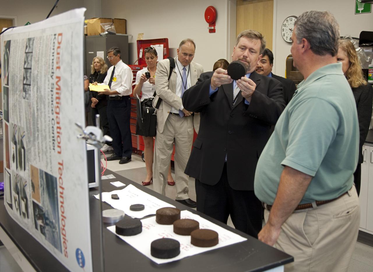 CAPE CANAVERAl, Fla. - Dr. Mason Peck, center, NASA's chief Technologist, listens as Michael Hogue, right, explains an innovation during Pecks' tour of the Space Life Sciences Laboratory at Kennedy. Peck toured the lab facility during a visit to the space center. Photo credit: NASA/Frankie Martin