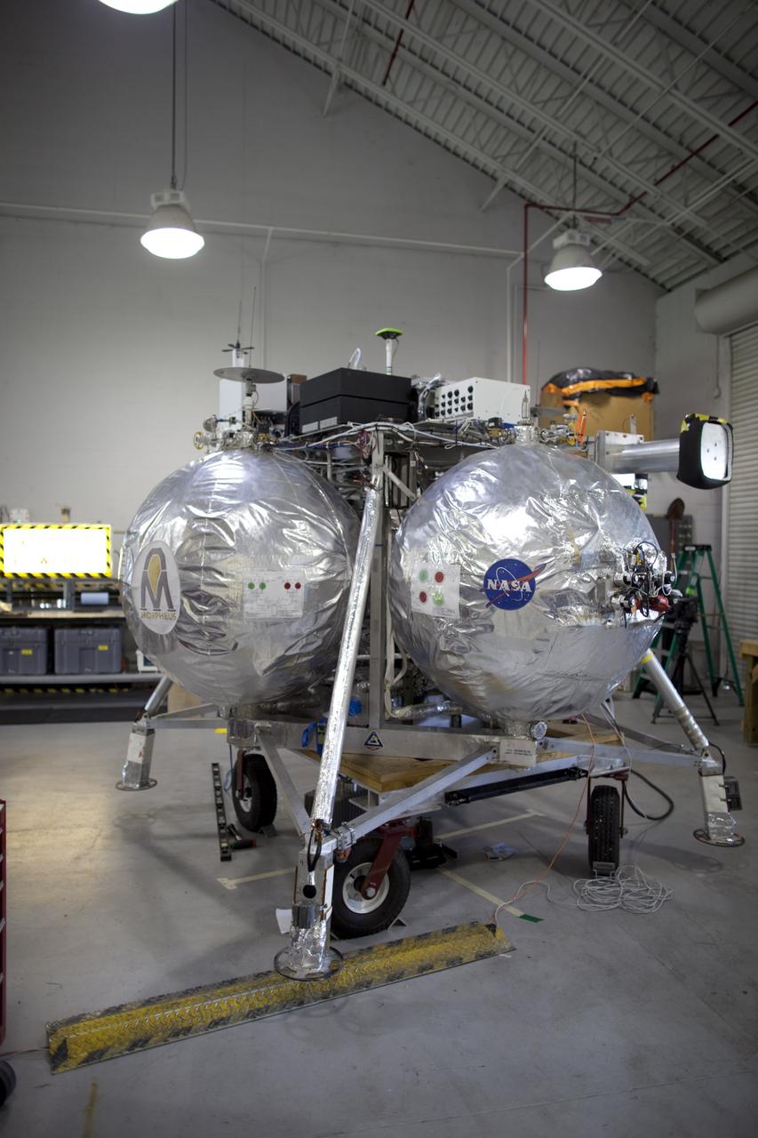 CAPE CANAVERAL, Fla. - NASA's Morpheus lander, a vertical test bed vehicle, is being checked out in a building at the Shuttle Landing Facility, or SLF, at the Kennedy Space Center in Florida. Morpheus is designed to demonstrate new green propellant propulsion systems and autonomous landing and an Autonomous Landing and Hazard Avoidance Technology, or ALHAT, system. Checkout of the prototype lander has been ongoing at NASA’s Johnson Space Center in Houston in preparation for its first free flight. The SLF site will provide the lander with the kind of field necessary for realistic testing. Project Morpheus is one of 20 small projects comprising the Advanced Exploration Systems, or AES, program in NASA’s Human Exploration and Operations Mission Directorate. AES projects pioneer new approaches for rapidly developing prototype systems, demonstrating key capabilities and validating operational concepts for future human missions beyond Earth orbit. For more information on Project Morpheus, visit http://www.nasa.gov/centers/johnson/exploration/morpheus/index.html Photo credit: NASA/Dimitri Gerondidakis