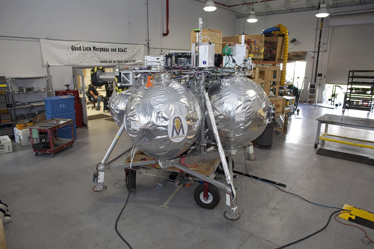 CAPE CANAVERAL, Fla. - NASA's Morpheus lander, a vertical test bed vehicle, is being checked out in a building at the Shuttle Landing Facility, or SLF, at the Kennedy Space Center in Florida. Morpheus is designed to demonstrate new green propellant propulsion systems and autonomous landing and an Autonomous Landing and Hazard Avoidance Technology, or ALHAT, system. Checkout of the prototype lander has been ongoing at NASA’s Johnson Space Center in Houston in preparation for its first free flight. The SLF site will provide the lander with the kind of field necessary for realistic testing. Project Morpheus is one of 20 small projects comprising the Advanced Exploration Systems, or AES, program in NASA’s Human Exploration and Operations Mission Directorate. AES projects pioneer new approaches for rapidly developing prototype systems, demonstrating key capabilities and validating operational concepts for future human missions beyond Earth orbit. For more information on Project Morpheus, visit http://www.nasa.gov/centers/johnson/exploration/morpheus/index.html Photo credit: NASA/Dimitri Gerondidakis