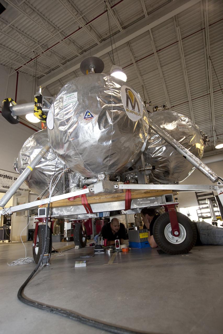CAPE CANAVERAL, Fla. - NASA's Morpheus lander, a vertical test bed vehicle, is checked out by technicians in a building at the Shuttle Landing Facility, or SLF, at the Kennedy Space Center in Florida. Morpheus is designed to demonstrate new green propellant propulsion systems and autonomous landing and an Autonomous Landing and Hazard Avoidance Technology, or ALHAT, system. Checkout of the prototype lander has been ongoing at NASA’s Johnson Space Center in Houston in preparation for its first free flight. The SLF site will provide the lander with the kind of field necessary for realistic testing. Project Morpheus is one of 20 small projects comprising the Advanced Exploration Systems, or AES, program in NASA’s Human Exploration and Operations Mission Directorate. AES projects pioneer new approaches for rapidly developing prototype systems, demonstrating key capabilities and validating operational concepts for future human missions beyond Earth orbit. For more information on Project Morpheus, visit http://www.nasa.gov/centers/johnson/exploration/morpheus/index.html Photo credit: NASA/Dimitri Gerondidakis