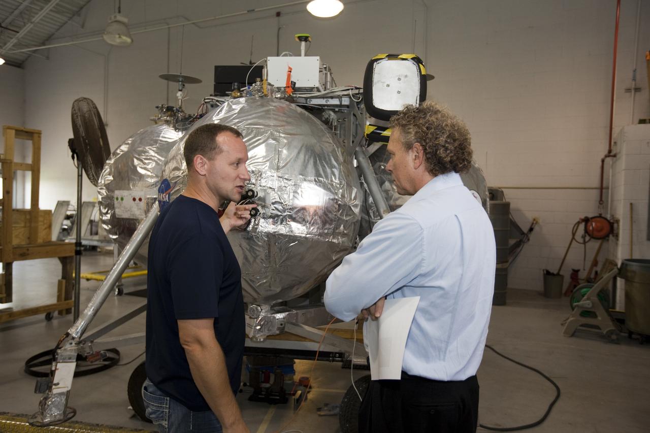 CAPE CANAVERAL, Fla. - Russell Romanella, director of Safety and Mission Assurance at NASA's Kennedy Space Center in Florida, right, is briefed on NASA's Morpheus lander, a vertical test bed vehicle. Morpheus is being checked out by technicians and engineers in a building at the Shuttle Landing Facility, or SLF, at Kennedy. Morpheus is designed to demonstrate new green propellant propulsion systems and autonomous landing and an Autonomous Landing and Hazard Avoidance Technology, or ALHAT, system.      Checkout of the prototype lander has been ongoing at NASA’s Johnson Space Center in Houston in preparation for its first free flight. The SLF site will provide the lander with the kind of field necessary for realistic testing. Project Morpheus is one of 20 small projects comprising the Advanced Exploration Systems, or AES, program in NASA’s Human Exploration and Operations Mission Directorate. AES projects pioneer new approaches for rapidly developing prototype systems, demonstrating key capabilities and validating operational concepts for future human missions beyond Earth orbit. For more information on Project Morpheus, visit http://www.nasa.gov/centers/johnson/exploration/morpheus/index.html  Photo credit: NASA/Dimitri Gerondidakis