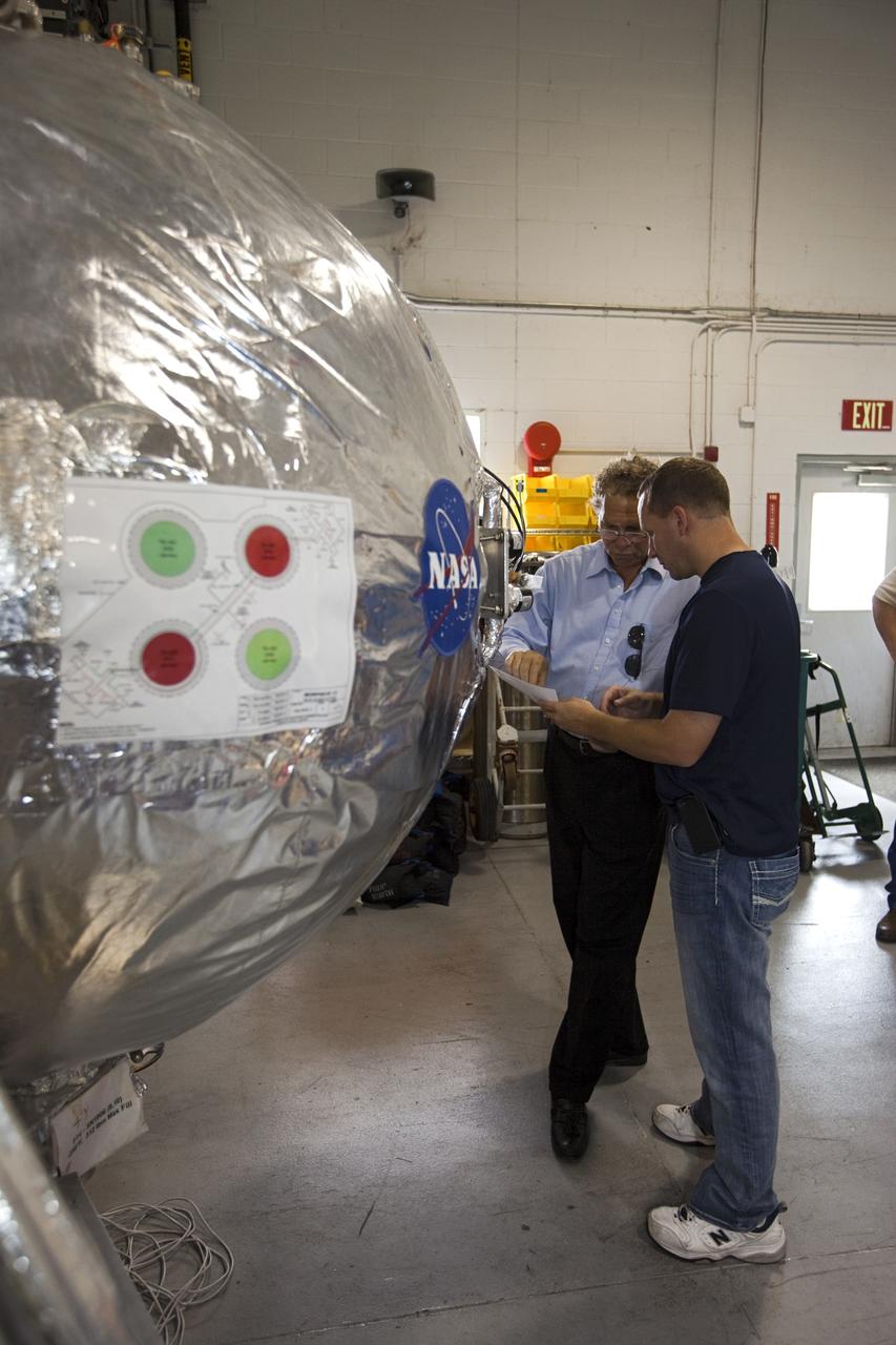 CAPE CANAVERAL, Fla. - Russell Romanella, director of Safety and Mission Assurance at NASA's Kennedy Space Center in Florida, left, is briefed on NASA's Morpheus lander, a vertical test bed vehicle. Morpheus is being checked out by technicians and engineers in a building at the Shuttle Landing Facility, or SLF, at Kennedy. Morpheus is designed to demonstrate new green propellant propulsion systems and autonomous landing and an Autonomous Landing and Hazard Avoidance Technology, or ALHAT, system.      Checkout of the prototype lander has been ongoing at NASA’s Johnson Space Center in Houston in preparation for its first free flight. The SLF site will provide the lander with the kind of field necessary for realistic testing. Project Morpheus is one of 20 small projects comprising the Advanced Exploration Systems, or AES, program in NASA’s Human Exploration and Operations Mission Directorate. AES projects pioneer new approaches for rapidly developing prototype systems, demonstrating key capabilities and validating operational concepts for future human missions beyond Earth orbit. For more information on Project Morpheus, visit http://www.nasa.gov/centers/johnson/exploration/morpheus/index.html  Photo credit: NASA/Dimitri Gerondidakis
