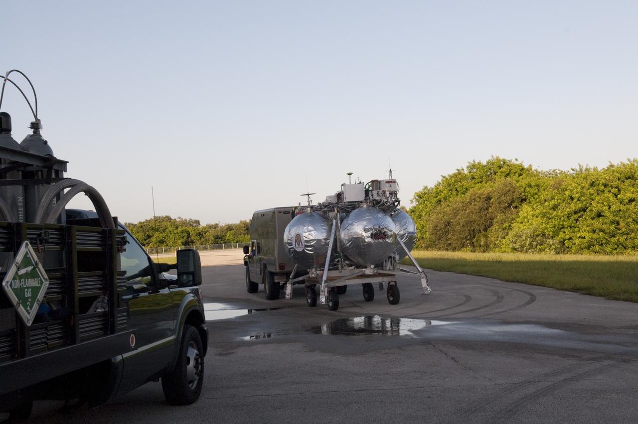 CAPE CANAVERAL, Fla. - NASA's Morpheus lander, a vertical test bed vehicle, is being transported out from its checkout building for a short trip to a launch position at the Shuttle Landing Facility, or SLF, at the Kennedy Space Center in Florida. Morpheus is designed to demonstrate new green propellant propulsion systems and autonomous landing and an Autonomous Landing and Hazard Avoidance Technology, or ALHAT, system. Checkout of the prototype lander has been ongoing at NASA’s Johnson Space Center in Houston in preparation for its first free flight. The SLF site will provide the lander with the kind of field necessary for realistic testing. Project Morpheus is one of 20 small projects comprising the Advanced Exploration Systems, or AES, program in NASA’s Human Exploration and Operations Mission Directorate. AES projects pioneer new approaches for rapidly developing prototype systems, demonstrating key capabilities and validating operational concepts for future human missions beyond Earth orbit. For more information on Project Morpheus, visit http://www.nasa.gov/centers/johnson/exploration/morpheus/index.html Photo credit: NASA/Dimitri Gerondidakis