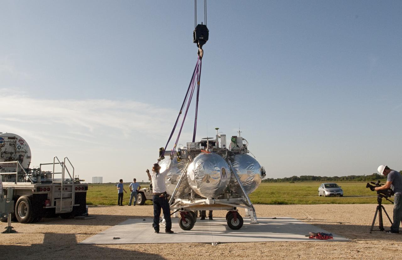 CAPE CANAVERAL, Fla. - A crane is being used to set up NASA's Morpheus lander, a vertical test bed vehicle, at its launch position along the runway at the Shuttle Landing Facility, or SLF, at the Kennedy Space Center in Florida. Morpheus is designed to demonstrate new green propellant propulsion systems and autonomous landing and an Autonomous Landing and Hazard Avoidance Technology, or ALHAT, system. Checkout of the prototype lander has been ongoing at NASA’s Johnson Space Center in Houston in preparation for its first free flight. The SLF site will provide the lander with the kind of field necessary for realistic testing. Project Morpheus is one of 20 small projects comprising the Advanced Exploration Systems, or AES, program in NASA’s Human Exploration and Operations Mission Directorate. AES projects pioneer new approaches for rapidly developing prototype systems, demonstrating key capabilities and validating operational concepts for future human missions beyond Earth orbit. For more information on Project Morpheus, visit http://www.nasa.gov/centers/johnson/exploration/morpheus/index.html Photo credit: NASA/Dimitri Gerondidakis