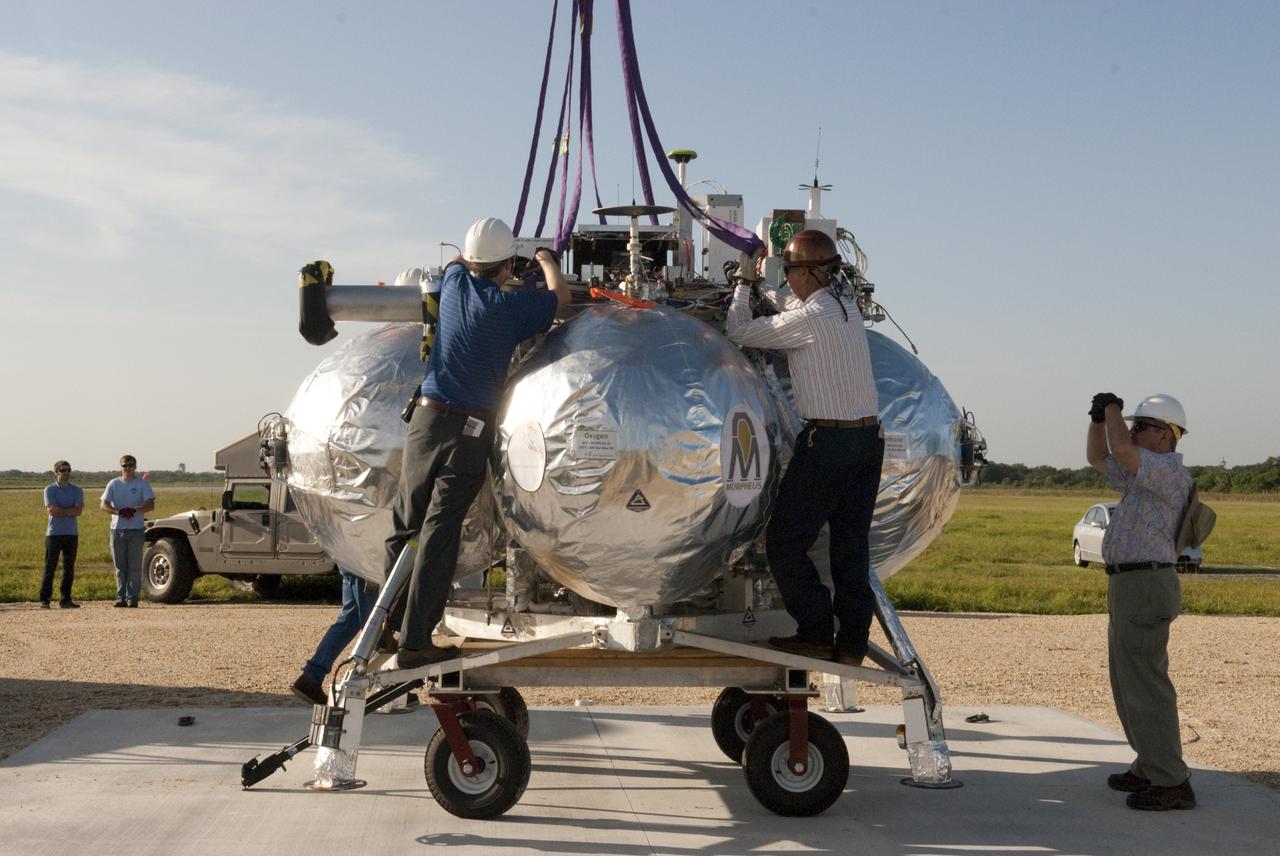 CAPE CANAVERAL, Fla. - Technicians secure connections for a crane which will be used to set up NASA's Morpheus lander, a vertical test bed vehicle, at its launch position along the runway at the Shuttle Landing Facility, or SLF, at the Kennedy Space Center in Florida. Morpheus is designed to demonstrate new green propellant propulsion systems and autonomous landing and an Autonomous Landing and Hazard Avoidance Technology, or ALHAT, system. Checkout of the prototype lander has been ongoing at NASA’s Johnson Space Center in Houston in preparation for its first free flight. The SLF site will provide the lander with the kind of field necessary for realistic testing. Project Morpheus is one of 20 small projects comprising the Advanced Exploration Systems, or AES, program in NASA’s Human Exploration and Operations Mission Directorate. AES projects pioneer new approaches for rapidly developing prototype systems, demonstrating key capabilities and validating operational concepts for future human missions beyond Earth orbit. For more information on Project Morpheus, visit http://www.nasa.gov/centers/johnson/exploration/morpheus/index.html Photo credit: NASA/Dimitri Gerondidakis