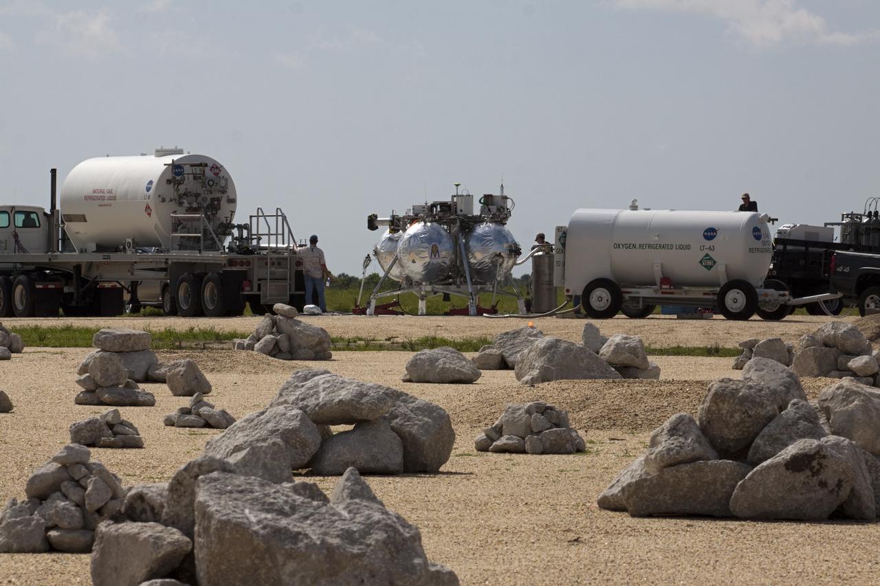 CAPE CANAVERAL, Fla. - At the north end of the Shuttle Landing Facility, or SLF, at the Kennedy Space Center in Florida, NASA's Morpheus lander, a vertical test bed vehicle, is being fueled. A rock and crater-filled planetary scape, seen in the foreground, has been built so engineers can test the Autonomous Landing and Hazard Avoidance Technology, or ALHAT, system on the Project Morpheus lander. Checkout of the prototype lander has been ongoing at NASA’s Johnson Space Center in Houston in preparation for its first free flight. The SLF site will provide the lander with the kind of field necessary for realistic testing. Project Morpheus is one of 20 small projects comprising the Advanced Exploration Systems, or AES, program in NASA’s Human Exploration and Operations Mission Directorate. AES projects pioneer new approaches for rapidly developing prototype systems, demonstrating key capabilities and validating operational concepts for future human missions beyond Earth orbit. For more information on Project Morpheus, visit http://www.nasa.gov/centers/johnson/exploration/morpheus/index.html Photo credit: NASA/Kim Shiflett
