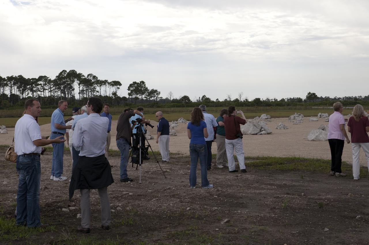 CAPE CANAVERAL, Fla. - At the Autonomous Landing and Hazard Avoidance Technology, or ALHAT, field at the north end of the Shuttle Landing Facility, or SLF, at NASA’s Kennedy Space Center in Florida, members of the media view the hazard field and speak with Morpheus managers. At far left, in the white shirt is Jon Olansen, Johnson Space Center Project Morpheus Manager. At left, in the blue shirt is Chirold Epp, JSC project manager for ALHAT.     Testing of the prototype lander had been ongoing at NASA’s Johnson Space Center in Houston in preparation for its first free-flight test at Kennedy Space Center. The SLF will provide the lander with the kind of field necessary for realistic testing, complete with rocks, craters and hazards to avoid. Morpheus utilizes an autonomous landing and hazard avoidance technology, or ALHAT, payload that will allow it to navigate to clear landing sites amidst rocks, craters and other hazards during its descent. Project Morpheus is one of 20 small projects comprising the Advanced Exploration Systems, or AES, program in NASA’s Human Exploration and Operations Mission Directorate. AES projects pioneer new approaches for rapidly developing prototype systems, demonstrating key capabilities and validating operational concepts for future human missions beyond Earth orbit. For more information on Project Morpheus, visit http://morpheuslander.jsc.nasa.gov/.  Photo credit: NASA/Kim Shiflett