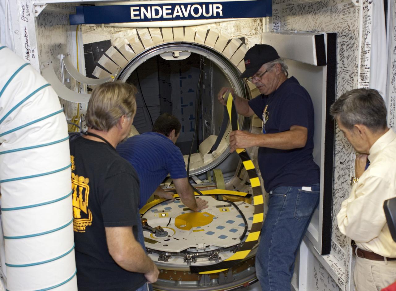 CAPE CANAVERAL, Fla. – In Orbiter Processing Facility Bay 2 at NASA’s Kennedy Space Center in Florida, Kennedy Space Center Director Bob Cabana, far right, watches as, left to right, United Space Alliance quality inspector Ken Carson, along with technicians Gary Hamilton and Joe Walsh remove protective covers in preparation to close the space shuttle Endeavour's hatch. The orbiter is undergoing final preparations for its cross-country ferry flight to California. The work is part of Transition and Retirement of the remaining space shuttles, Endeavour and Atlantis. Endeavour is being prepared for public display at the California Science Center in Los Angeles. Its ferry flight to California is targeted for mid-September. Endeavour was the last space shuttle added to NASA’s orbiter fleet. Over the course of its 19-year career, Endeavour spent 299 days in space during 25 missions. For more information, visit http://www.nasa.gov/transition Photo credit: NASA/ Jim Grossmann