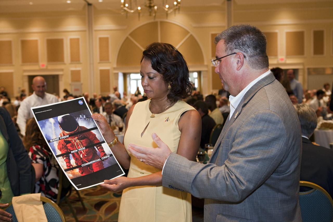 CAPE CANAVERAL, Fla. -- NASA Commercial Crew Program Manager Ed Mango, right, shows Florida's Lt. Gov. Jennifer Carroll the program's "Same Crew, New Ride" poster at the National Space Club Florida Committee's August luncheon at the Radisson Resort at the Port in Cape Canaveral, Fla. Mango was the event's guest speaker, discussing the innovative steps the agency is taking with industry partners to develop the next U.S. space transportation capability to and from low Earth orbit, which will eventually be available for use by the U.S. government and other commercial customers. To learn more about the Commercial Crew Program, visit www.nasa.gov/commercialcrew. Photo credit: Kim Shiflett
