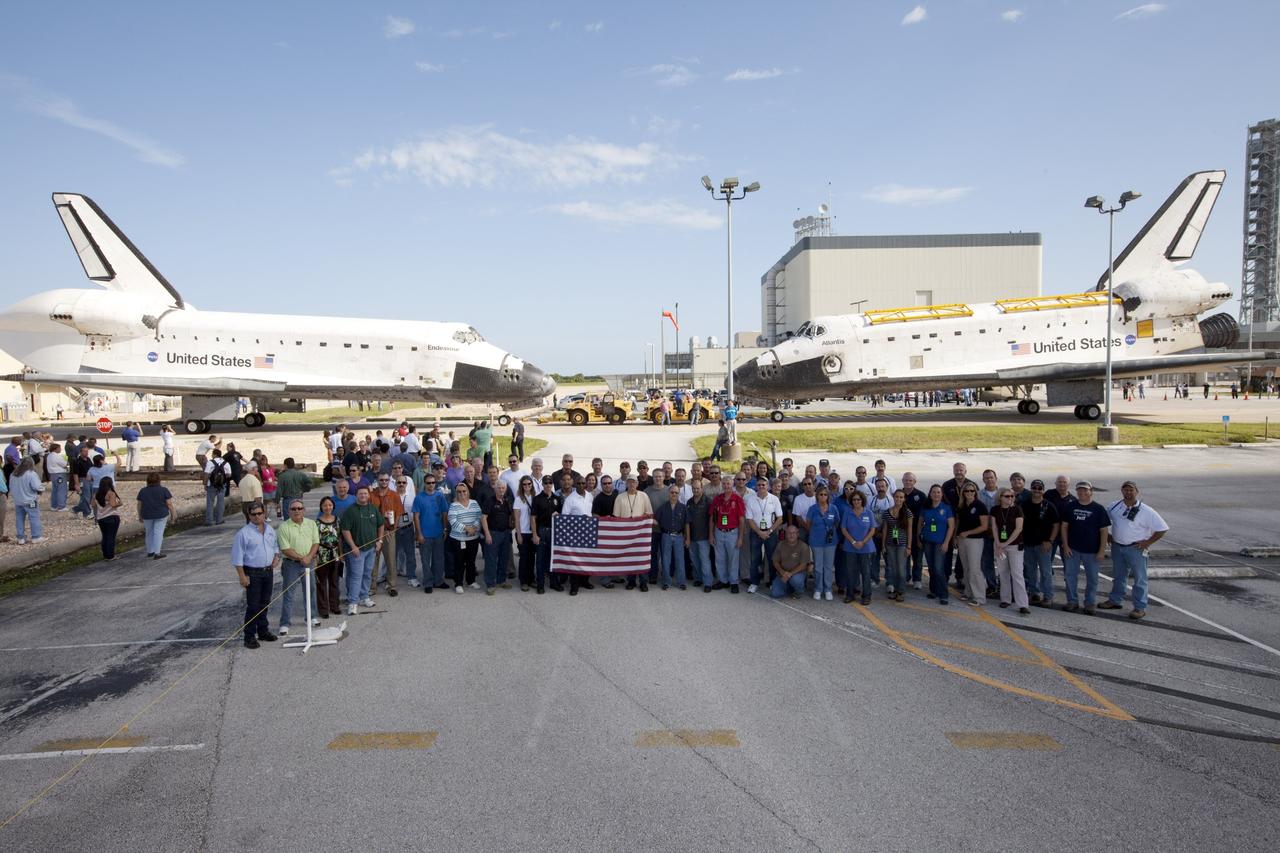 CAPE CANAVERAL, Fla. – Members of the Kennedy Space Center team who helped process the space shuttles Endeavour and Atlantis, gather for a group picture after the two spacecraft were brought together for a brief photo opportunity. Endeavour moved from Bay 2 of the Orbiter Processing Facility OPF to switch places with Atlantis which had been in Vehicle Assembly Building. In the OPF, Atlantis will undergo final preparations for its transfer to the Kennedy Space Center Visitor Complex targeted for November. The work is part of Transition and Retirement of the remaining space shuttles, Atlantis and Endeavour. Atlantis is being prepared for public display at Kennedy's Visitor Complex. Over the course of its 26-year career, Atlantis spent 293 days in space during 33 missions. For more information, visit http://www.nasa.gov/transition Photo credit: NASA/Kim Shiflett