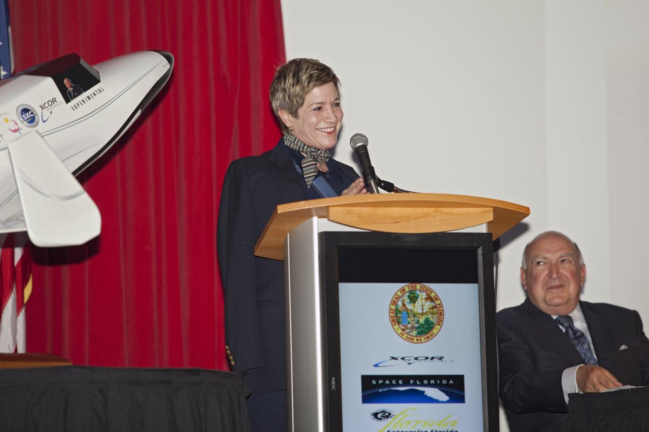 CAPE CANAVERAL, Fla. - At NASA's Kennedy Space Center in Florida, Lynda Weatherman, President of the Economic Development Commission of Florida Space Coast, addresses guests at a presentation during which XCOR Aerospace announced plans to open a manufacturing operation in Brevard. Space Florida President Frank DiBello is seated to the right.      The company's suborbital Lynx Mark II spacecraft possibly will take off and land at Kennedy's shuttle landing facility. XCOR Aerospace is a small, privately held California corporation with focus on the research, development, project management and production of reusable launch vehicles, rocket engines and rocket propulsion systems. XCOR will focus on space tourism, experimental flights and launching satellites. Photo credit: NASA/ Frankie Martin