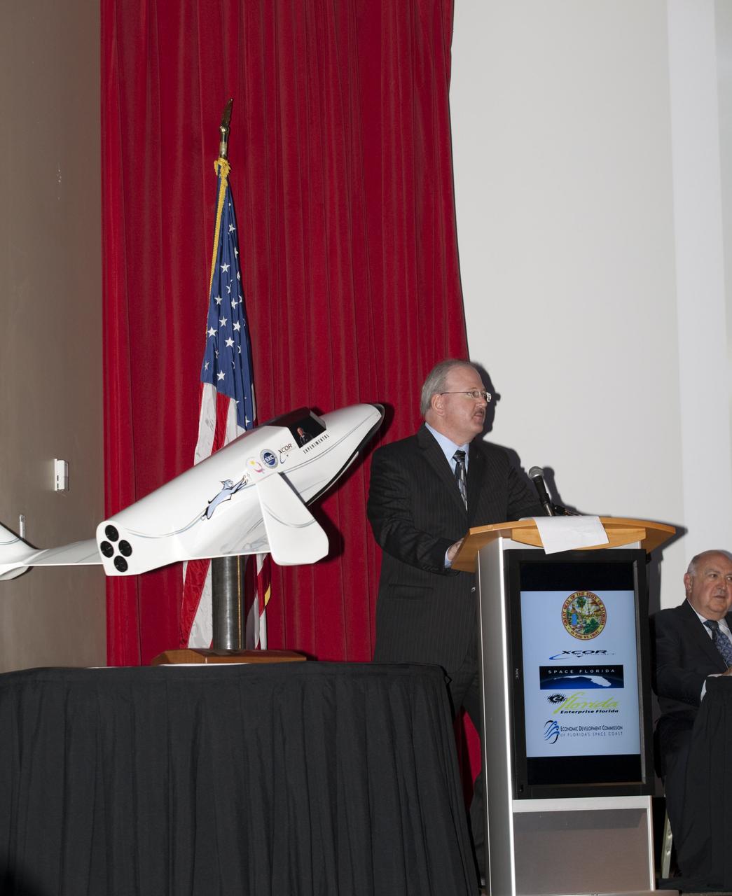 CAPE CANAVERAL, Fla. - At NASA's Kennedy Space Center in Florida, XCOR President Jeff Greason addresses guests at a presentation during which XCOR Aerospace announced plans to open a manufacturing operation in Brevard. Space Florida President Frank DiBello is seated to the right.      The company's suborbital Lynx Mark II spacecraft possibly will take off and land at Kennedy's shuttle landing facility. XCOR Aerospace is a small, privately held California corporation with focus on the research, development, project management and production of reusable launch vehicles, rocket engines and rocket propulsion systems. XCOR will focus on space tourism, experimental flights and launching satellites. Photo credit: NASA/ Frankie Martin