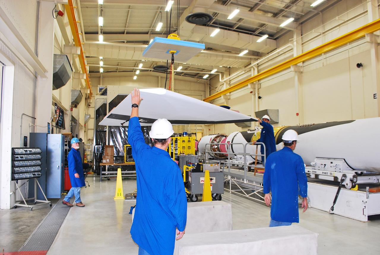 Vandenberg Air Force Base, Calif. – Inside a processing facility at Vandenberg Air Force Base in California, technicians assist as a crane moves the wing closer for a fit check with the Orbital Sciences Pegasus XL launch vehicle.    NASA’s Interface Region Imaging Spectrograph, or IRIS, spacecraft will launch aboard the Pegasus XL in late 2012. IRIS will open a new window of discovery by tracing the flow of energy and plasma through the chromospheres and transition region into the sun’s corona using spectrometry and imaging. IRIS fills a crucial gap in our ability to advance studies of the sun-to-Earth connection by tracing the flow of energy and plasma through the foundation of the corona and heliosphere, or region around the sun. Photo credit: NASA/Randy Beaudoin