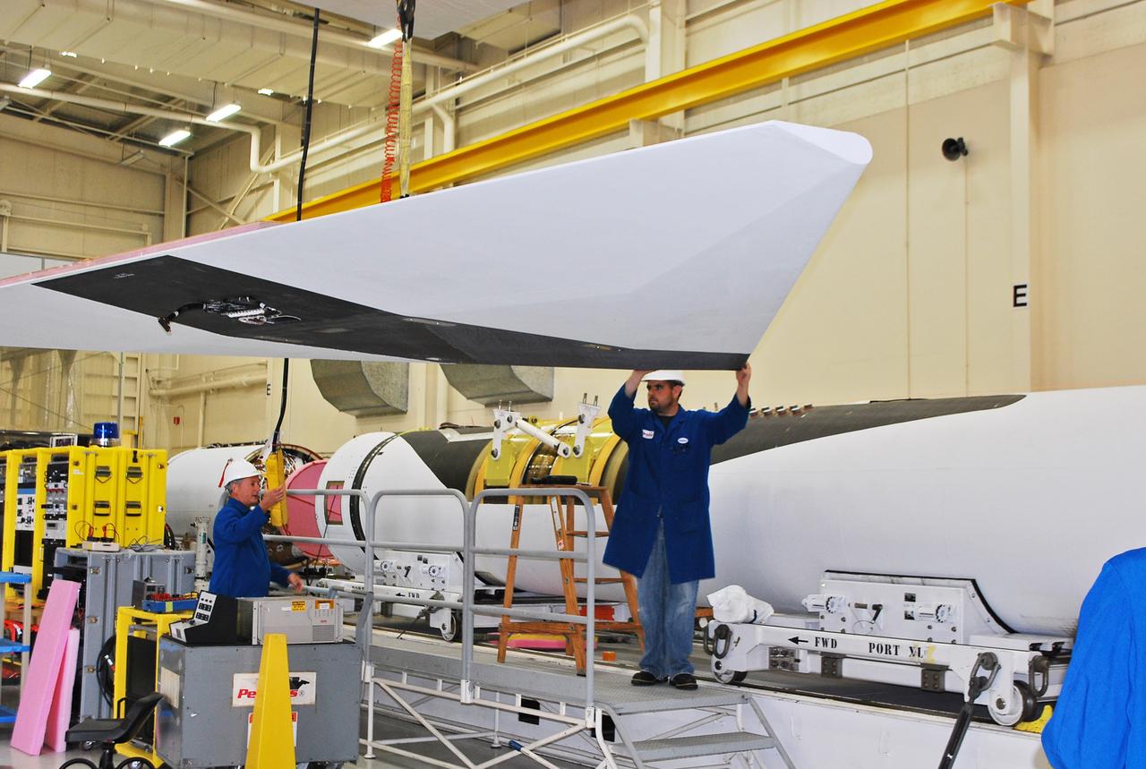 Vandenberg Air Force Base, Calif. – Inside a processing facility at Vandenberg Air Force Base in California, technicians assist as a crane moves the wing closer for a fit check with the Orbital Sciences Pegasus XL launch vehicle.    NASA’s Interface Region Imaging Spectrograph, or IRIS, spacecraft will launch aboard the Pegasus XL in late 2012. IRIS will open a new window of discovery by tracing the flow of energy and plasma through the chromospheres and transition region into the sun’s corona using spectrometry and imaging. IRIS fills a crucial gap in our ability to advance studies of the sun-to-Earth connection by tracing the flow of energy and plasma through the foundation of the corona and heliosphere, or region around the sun. Photo credit: NASA/Randy Beaudoin