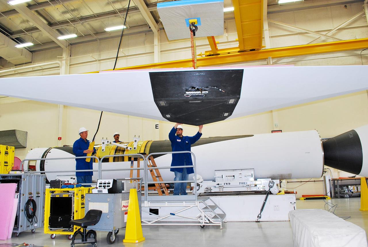 Vandenberg Air Force Base, Calif. – Inside a processing facility at Vandenberg Air Force Base in California, technicians assist as a crane moves the wing closer for a fit check with the Orbital Sciences Pegasus XL launch vehicle.    NASA’s Interface Region Imaging Spectrograph, or IRIS, spacecraft will launch aboard the Pegasus XL in late 2012. IRIS will open a new window of discovery by tracing the flow of energy and plasma through the chromospheres and transition region into the sun’s corona using spectrometry and imaging. IRIS fills a crucial gap in our ability to advance studies of the sun-to-Earth connection by tracing the flow of energy and plasma through the foundation of the corona and heliosphere, or region around the sun. Photo credit: NASA/Randy Beaudoin
