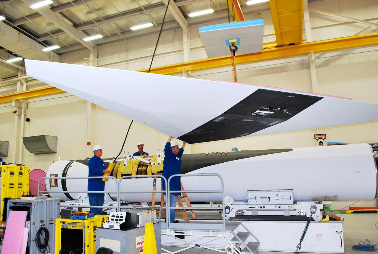 Vandenberg Air Force Base, Calif. – Inside a processing facility at Vandenberg Air Force Base in California, technicians assist as a crane lowers the wing closer for a fit check with the Orbital Sciences Pegasus XL launch vehicle.    NASA’s Interface Region Imaging Spectrograph, or IRIS, spacecraft will launch aboard the Pegasus XL in late 2012. IRIS will open a new window of discovery by tracing the flow of energy and plasma through the chromospheres and transition region into the sun’s corona using spectrometry and imaging. IRIS fills a crucial gap in our ability to advance studies of the sun-to-Earth connection by tracing the flow of energy and plasma through the foundation of the corona and heliosphere, or region around the sun. Photo credit: NASA/Randy Beaudoin