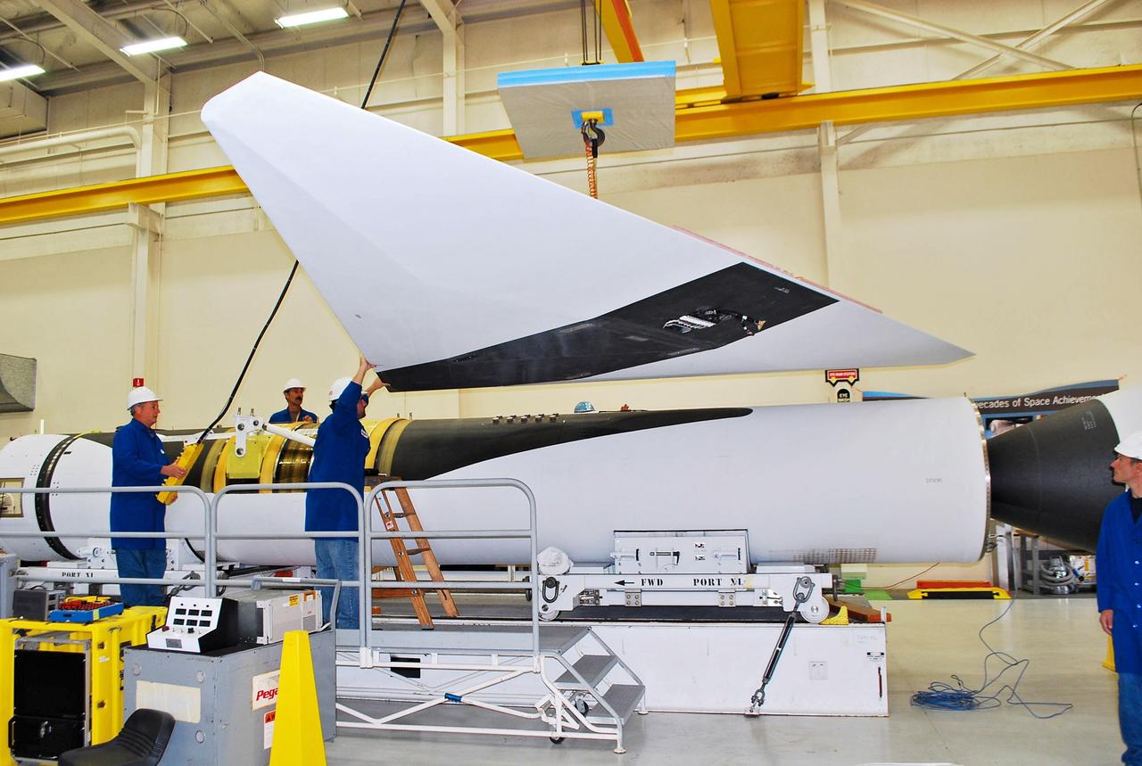 Vandenberg Air Force Base, Calif. – Inside a processing facility at Vandenberg Air Force Base in California, technicians assist as a crane lowers the wing closer for a fit check with the Orbital Sciences Pegasus XL launch vehicle.    NASA’s Interface Region Imaging Spectrograph, or IRIS, spacecraft will launch aboard the Pegasus XL in late 2012. IRIS will open a new window of discovery by tracing the flow of energy and plasma through the chromospheres and transition region into the sun’s corona using spectrometry and imaging. IRIS fills a crucial gap in our ability to advance studies of the sun-to-Earth connection by tracing the flow of energy and plasma through the foundation of the corona and heliosphere, or region around the sun. Photo credit: NASA/Randy Beaudoin