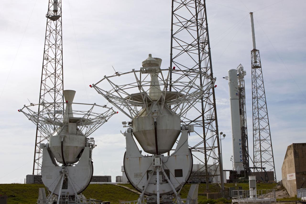 CAPE CANAVERAL, Fla. - Just prior to the wet dress rehearsal for the SpaceX Falcon 9 rocket, the frameworks of the former MILA tracking station S-band 9-meter tracking antennas are seen with the Falcon 9 rocket. These antennas were used by NASA during the Apollo and space shuttle programs. They are being re-purposed by SpaceX. The antennas will moved to another location, reassembled and refurbished for tracking during future SpaceX launches and missions.   The SpaceX CRS contract with NASA provides for 12 cargo resupply missions to the station through 2015, the first of which is targeted to launch in October 2012.SpaceX became the first private company to berth a spacecraft with the space station in 2012 during its final demonstration flight under the Commercial Orbital Transportation Services, or COTS, program managed by NASA's Johnson Space Center in Houston. Photo credit: NASA/Jim Grossmann