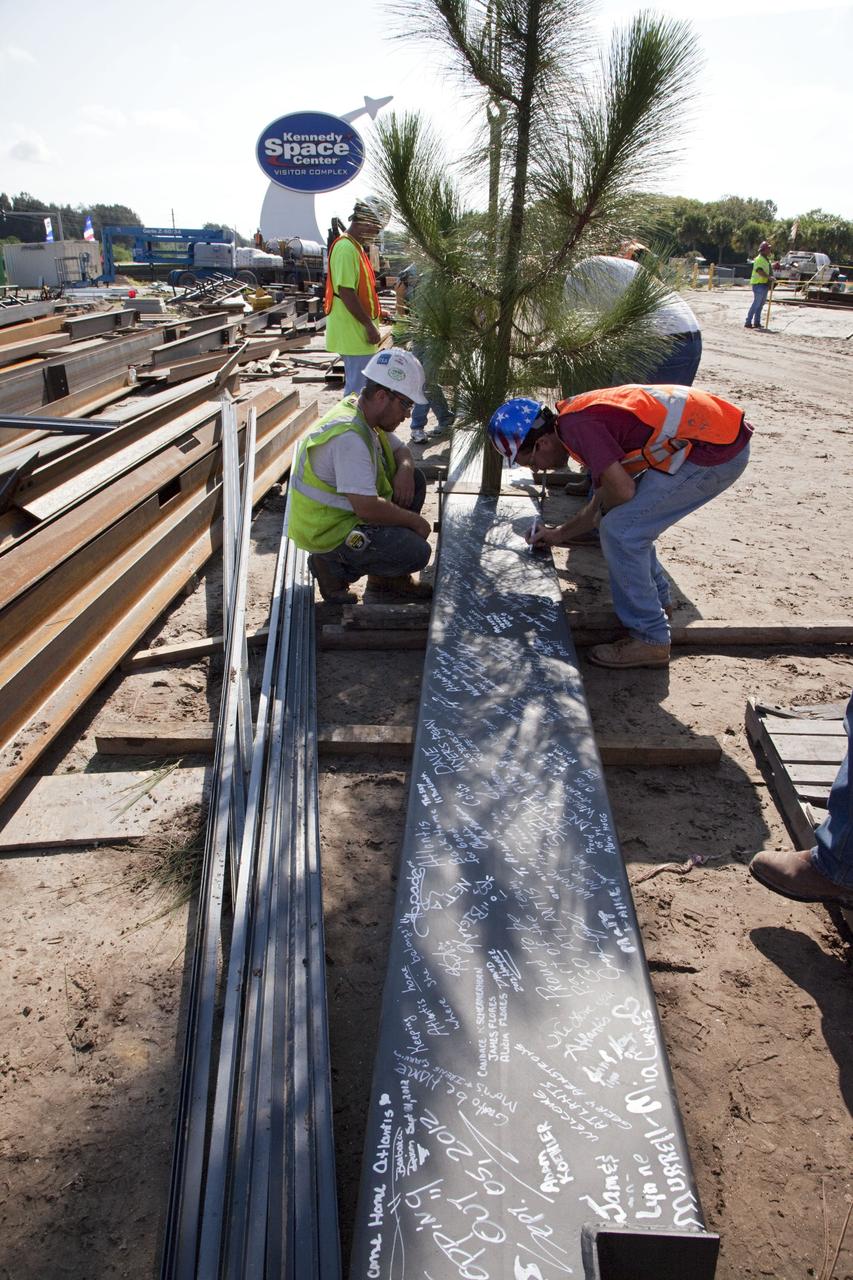 CAPE CANAVERAL, Fla. – Workers sign a steel beam before it is placed at the highest point of a new exhibit facility under construction at the Kennedy Space Center Visitor Complex. The 90,000-square-foot facility will house space shuttle Atlantis and 62 shuttle program exhibits. Photo credit: NASA/Kim Shiflett