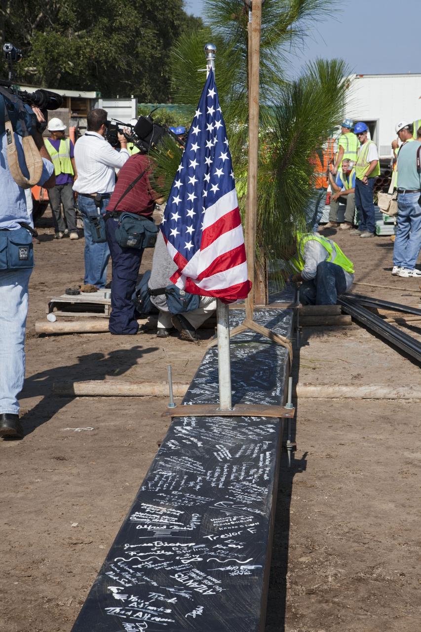 CAPE CANAVERAL, Fla. – Workers sign a steel beam before it is placed at the highest point of a new exhibit facility under construction at the Kennedy Space Center Visitor Complex. The 90,000-square-foot facility will house space shuttle Atlantis and 62 shuttle program exhibits. Photo credit: NASA/Kim Shiflett