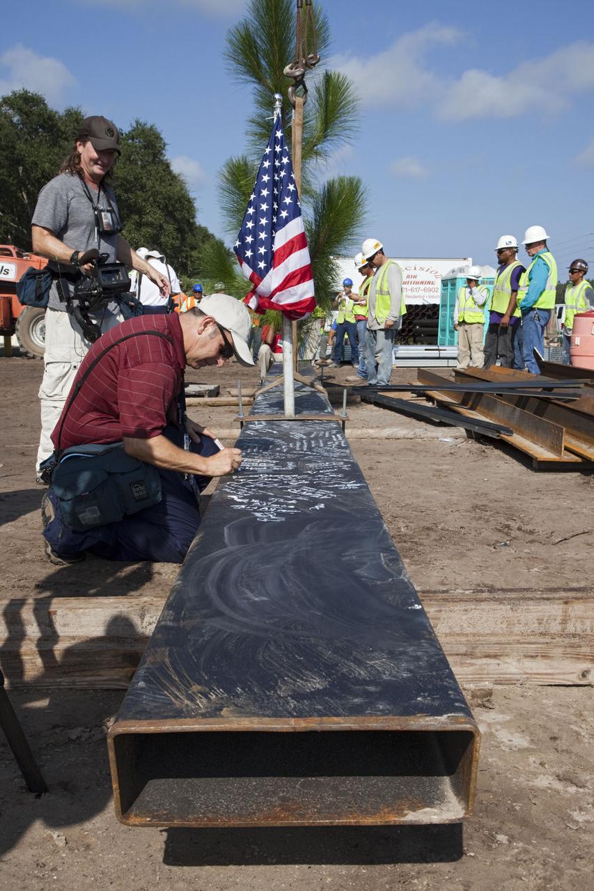 CAPE CANAVERAL, Fla. – An event observer signs a steel beam before it is placed at the highest point of a new exhibit facility under construction at the Kennedy Space Center Visitor Complex. The 90,000-square-foot facility will house space shuttle Atlantis and 62 shuttle program exhibits. Photo credit: NASA/Kim Shiflett