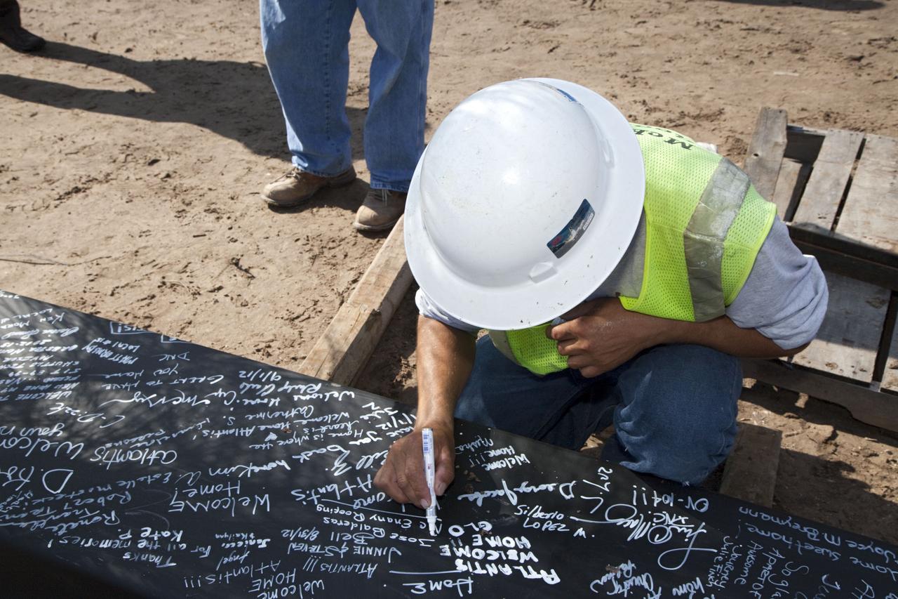 CAPE CANAVERAL, Fla. – A worker signs a steel beam before it is placed at the highest point of a new exhibit facility under construction at the Kennedy Space Center Visitor Complex. The 90,000-square-foot facility will house space shuttle Atlantis and 62 shuttle program exhibits. Photo credit: NASA/Kim Shiflett