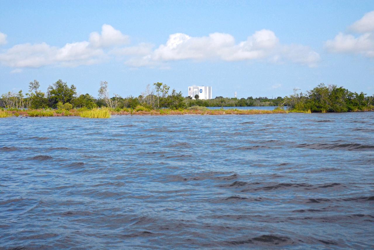 CAPE CANAVERAL, Fla. – The Vehicle Assembly Building, or VAB, is seen in the distance during a field-guided boat tour of NASA's Kennedy Space Center in Florida. As part of the center's first-ever Innovation Expo, the tour, called "Living Outdoor Laboratory for Environmental Sustainability," is giving employees the opportunity to see the unique estuarine ecosystems that are protected from development by the presence of Kennedy and the Merritt Island National Wildlife Refuge.       The diverse and healthy area encompassing about 140,000 acres of central Florida's east coast has been closed to the public for 50 years, allowing the coastal dunes, saltwater estuaries and marshes, freshwater impoundments, scrub, pine flatwoods, and hardwood hammocks to provide habitats for more than 1,000 species of plants and animals. Innovation Expo is showcasing the innovative work taking place throughout the center's facilities and labs to encourage employees to work together to solve future challenges. For more information, visit http://www.nasa.gov/kennedy. Photo credit: NASA