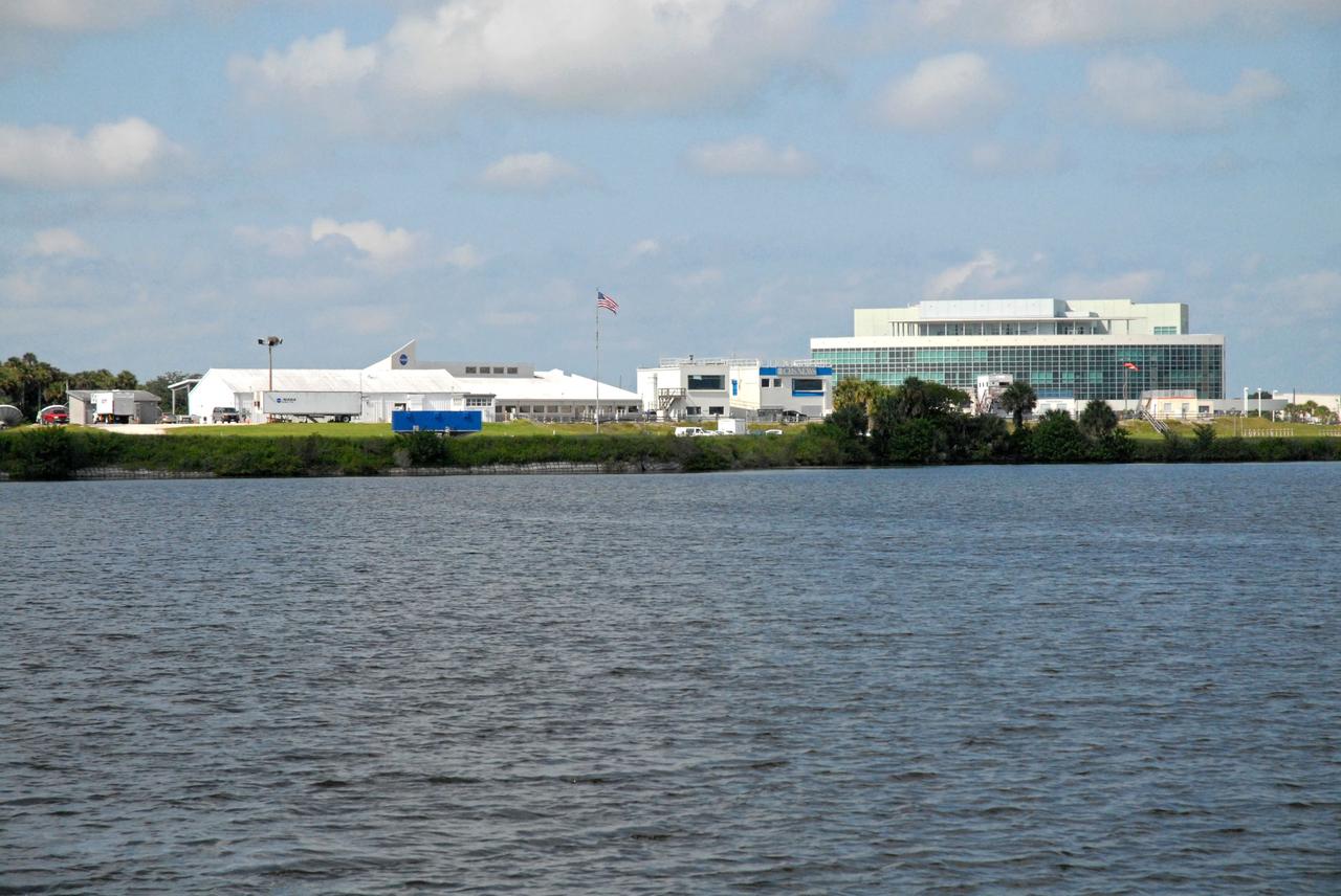 CAPE CANAVERAL, Fla. – The NASA News Center and Operations Support Building II, or OSBII, in Launch Complex 39 are seen in the distance during a field-guided boat tour of NASA's Kennedy Space Center in Florida. As part of the center's first-ever Innovation Expo, the tour, called "Living Outdoor Laboratory for Environmental Sustainability," is giving employees the opportunity to see the unique estuarine ecosystems that are protected from development by the presence of Kennedy and the Merritt Island National Wildlife Refuge.       The diverse and healthy area encompassing about 140,000 acres of central Florida's east coast has been closed to the public for 50 years, allowing the coastal dunes, saltwater estuaries and marshes, freshwater impoundments, scrub, pine flatwoods, and hardwood hammocks to provide habitats for more than 1,000 species of plants and animals. Innovation Expo is showcasing the innovative work taking place throughout the center's facilities and labs to encourage employees to work together to solve future challenges. For more information, visit http://www.nasa.gov/kennedy. Photo credit: NASA