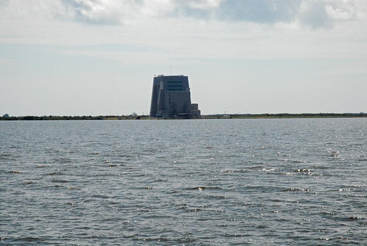 CAPE CANAVERAL, Fla. – Cape Canaveral Air Force Station's Solid Motor Assembly Building, or SMAB, is seen in the distance during a field-guided boat tour of NASA's Kennedy Space Center in Florida. As part of the center's first-ever Innovation Expo, the tour, called "Living Outdoor Laboratory for Environmental Sustainability," is giving employees the opportunity to see the unique estuarine ecosystems that are protected from development by the presence of Kennedy and the Merritt Island National Wildlife Refuge.         The diverse and healthy area encompassing about 140,000 acres of central Florida's east coast has been closed to the public for 50 years, allowing the coastal dunes, saltwater estuaries and marshes, freshwater impoundments, scrub, pine flatwoods, and hardwood hammocks to provide habitats for more than 1,000 species of plants and animals. Innovation Expo is showcasing the innovative work taking place throughout the center's facilities and labs to encourage employees to work together to solve future challenges. For more information, visit http://www.nasa.gov/kennedy. Photo credit: NASA