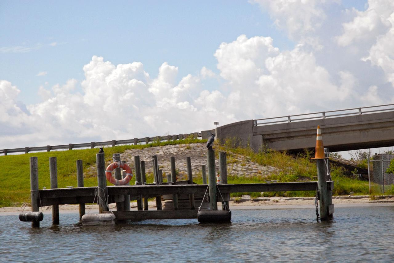 CAPE CANAVERAL, Fla. – A boat dock and the Roy D. Bridges Jr. Bridge connecting NASA Kennedy Space Center's Industrial Area to Cape Canaveral Air Force Station's Industrial Area are seen during a field-guided boat tour. As part of the Kennedy's first-ever Innovation Expo, the tour, called "Living Outdoor Laboratory for Environmental Sustainability," is giving employees the opportunity to see the unique estuarine ecosystems that are protected from development by the presence of the center and the Merritt Island National Wildlife Refuge.       The diverse and healthy area encompassing about 140,000 acres of central Florida's east coast has been closed to the public for 50 years, allowing the coastal dunes, saltwater estuaries and marshes, freshwater impoundments, scrub, pine flatwoods, and hardwood hammocks to provide habitats for more than 1,000 species of plants and animals. Innovation Expo is showcasing the innovative work taking place throughout the center's facilities and labs to encourage employees to work together to solve future challenges. For more information, visit http://www.nasa.gov/kennedy. Photo credit: NASA