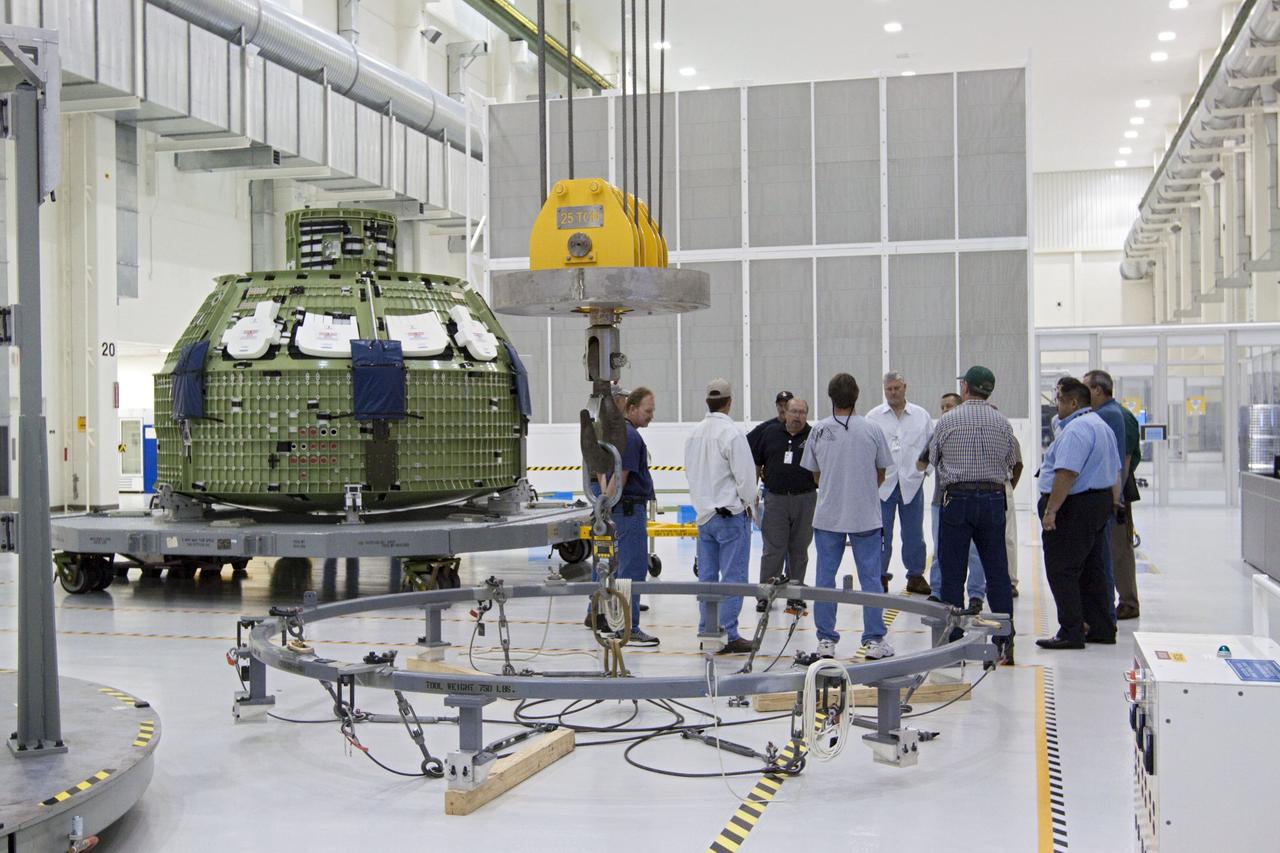 CAPE CANAVERAL, Fla. – Inside the Operations and Checkout Building high bay at NASA’s Kennedy Space Center in Florida, workers meet to go over the details for lifting and moving the Orion Exploration Flight Test 1 crew module on to the base of a birdcage tool. The birdcage will be used to continue installation of external components in preparation for Orion’s first uncrewed test flight in 2014 atop a Delta IV rocket. Orion is the exploration spacecraft designed to carry crews to space beyond low Earth orbit. It will provide emergency abort capability, sustain the crew during the space travel and provide safe re-entry from deep space return velocities. A second uncrewed flight test is scheduled for 2017 on NASA’s Space Launch System rocket. For more information, visit http://www.nasa.gov/orion. Photo credit: NASA/Kim Shiflett