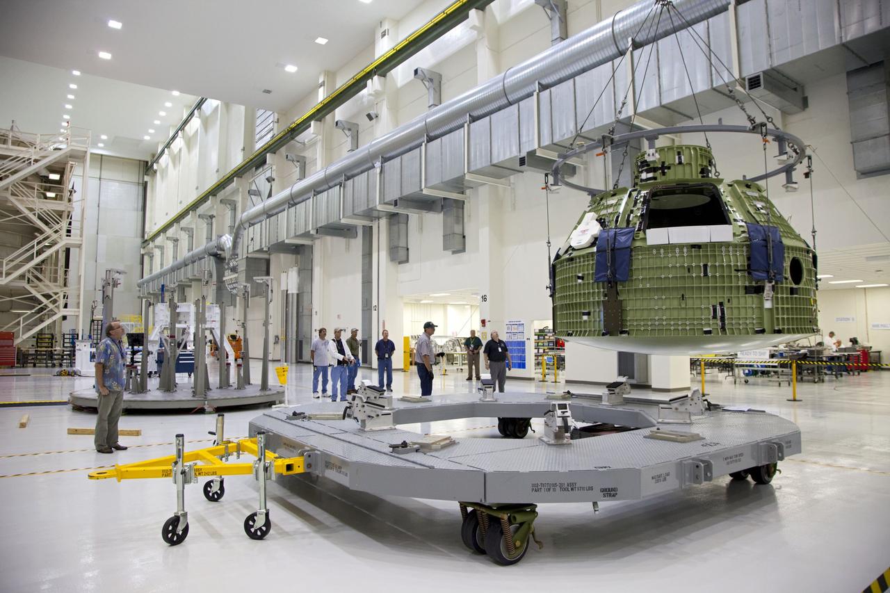 CAPE CANAVERAL, Fla. – Inside the Operations and Checkout Building at NASA’s Kennedy Space Center in Florida, technicians monitor the progress as a crane is used to move the Orion Exploration Flight Test 1 crew module to the base of a birdcage tool. The birdcage will be used to continue installation of external components in preparation for Orion’s first uncrewed test flight in 2014 atop a Delta IV rocket. Orion is the exploration spacecraft designed to carry crews to space beyond low Earth orbit. It will provide emergency abort capability, sustain the crew during the space travel and provide safe re-entry from deep space return velocities. A second uncrewed flight test is scheduled for 2017 on NASA’s Space Launch System rocket. For more information, visit http://www.nasa.gov/orion. Photo credit: NASA/Kim Shiflett