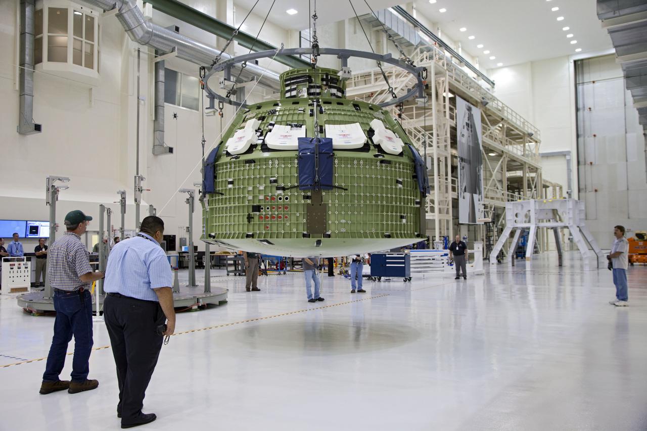 CAPE CANAVERAL, Fla. – Inside the Operations and Checkout Building at NASA’s Kennedy Space Center in Florida, technicians monitor the progress as a crane is used to move the Orion Exploration Flight Test 1 crew module to the base of a birdcage tool. The birdcage will be used to continue installation of external components in preparation for Orion’s first uncrewed test flight in 2014 atop a Delta IV rocket. Orion is the exploration spacecraft designed to carry crews to space beyond low Earth orbit. It will provide emergency abort capability, sustain the crew during the space travel and provide safe re-entry from deep space return velocities. A second uncrewed flight test is scheduled for 2017 on NASA’s Space Launch System rocket. For more information, visit http://www.nasa.gov/orion. Photo credit: NASA/Kim Shiflett